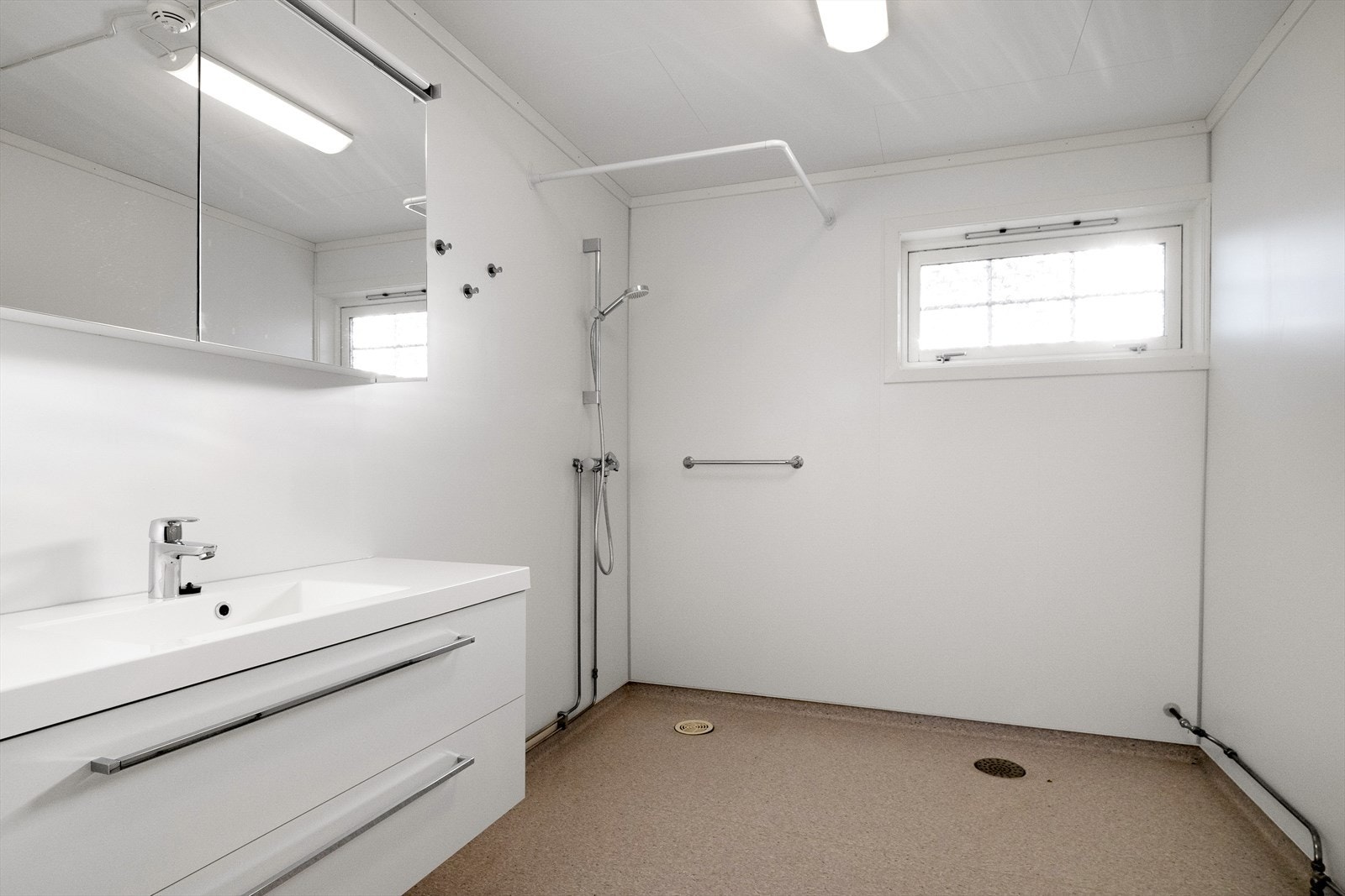 Rommet er innredet med et servantskap med servant, et gulvmontert toalett og en vegghengt dusj. Galleribilde