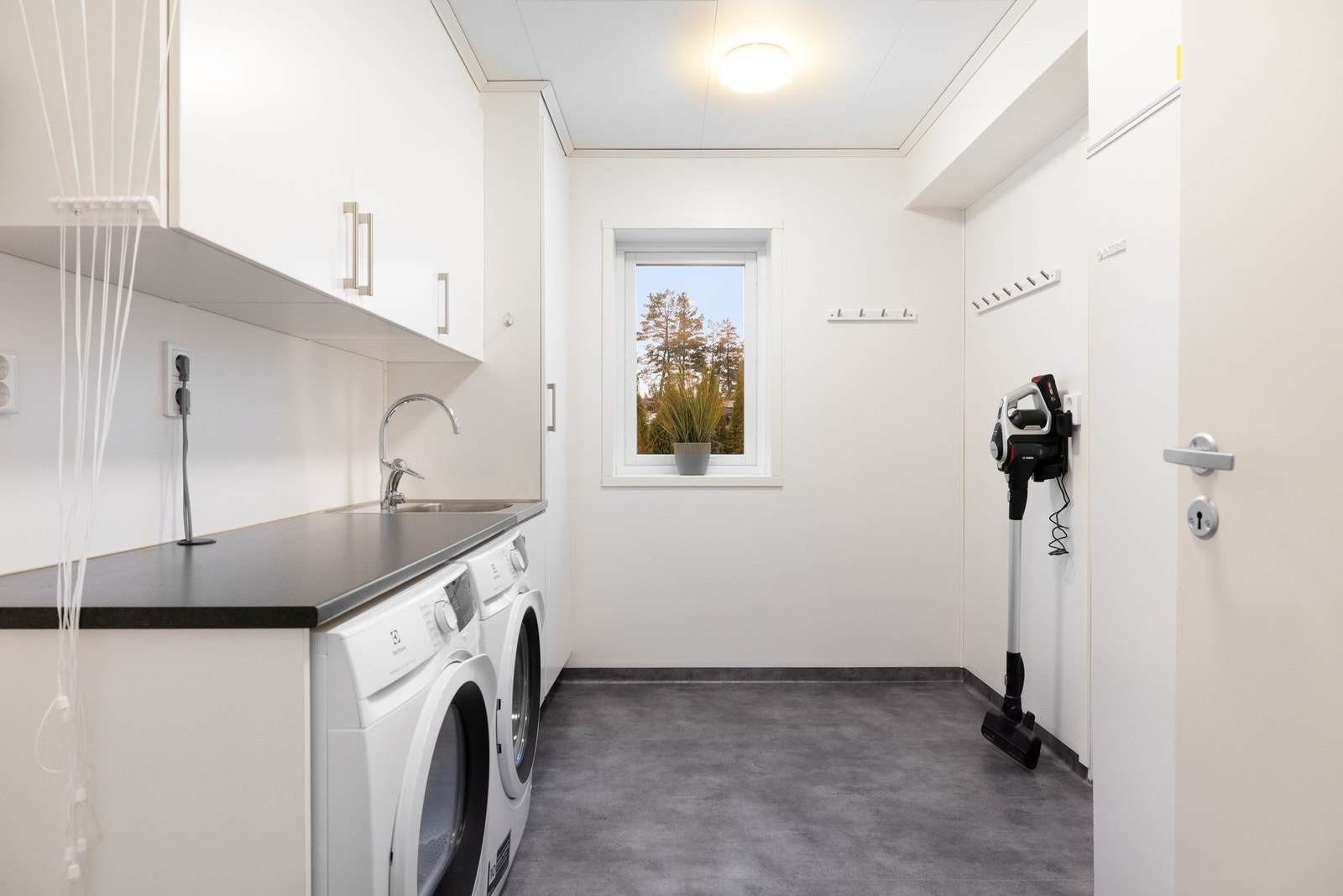 Meget praktisk vaskerom med utgang ut til terrasse/hage. På vaskerommet finner vi en god del av de tekniske løsningene. Blant annet står det en NIBE F750 avtrekksvarmepumpe som gir varme, varmtvann og ventilasjon. Galleribilde