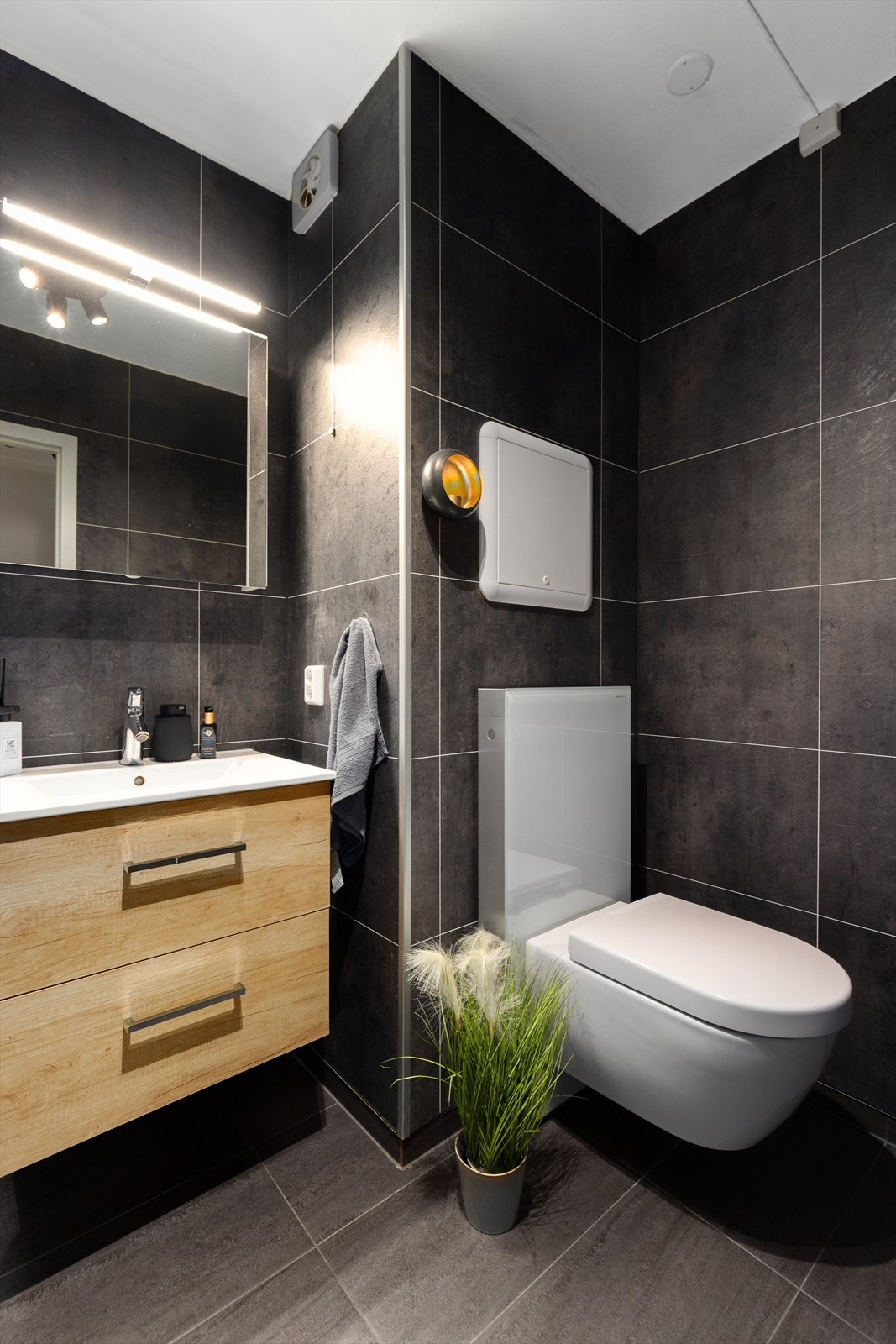 Pen servantinnredning med to skuffer og heldekkende servantplate, samt praktisk speil med integrert belysning på vegg. Galleribilde