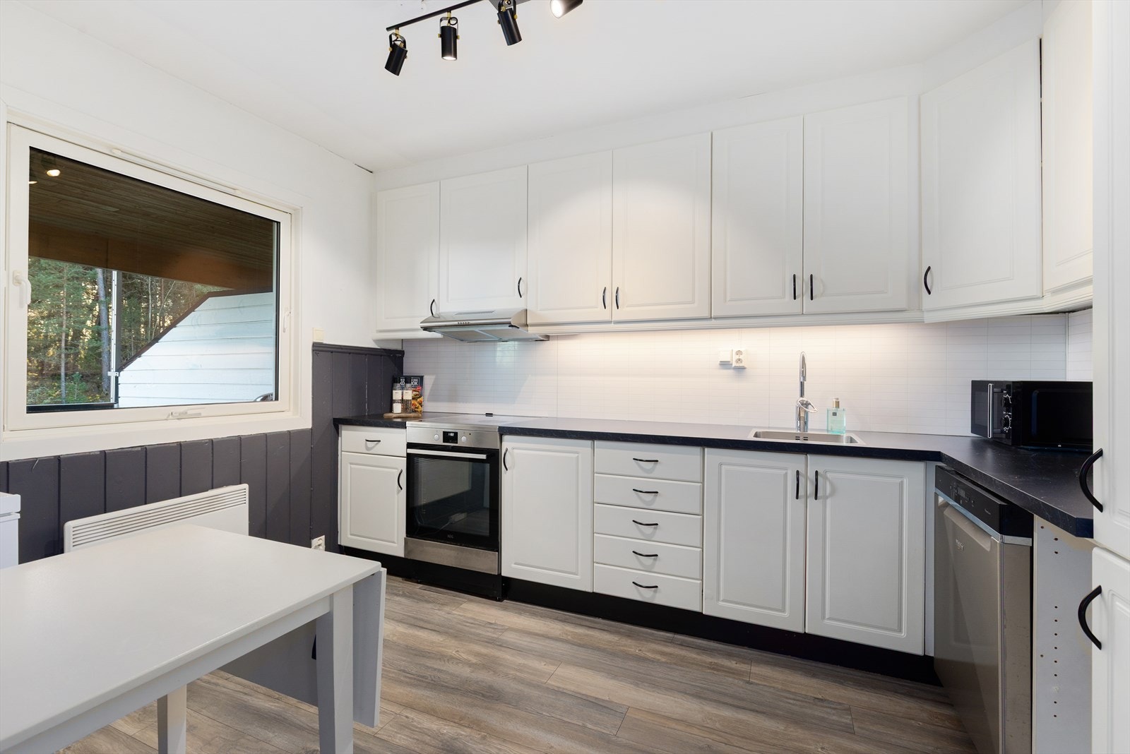 Delikat og godt utnyttet kjøkken med lys, takhøy kjøkkeninnredning. Innredningen har godt med oppbevaringsplass i skap- og skuffeseksjoner. Profilerte fronter i hvit og laminat benkeplate med gode arbeidsflater. Galleribilde