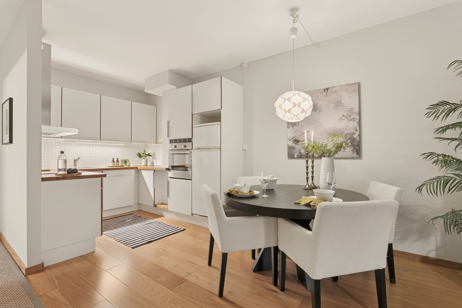 Delikat kjøkken med lyse slette fronter og heltre benkeplate med fliser over benk Galleribilde