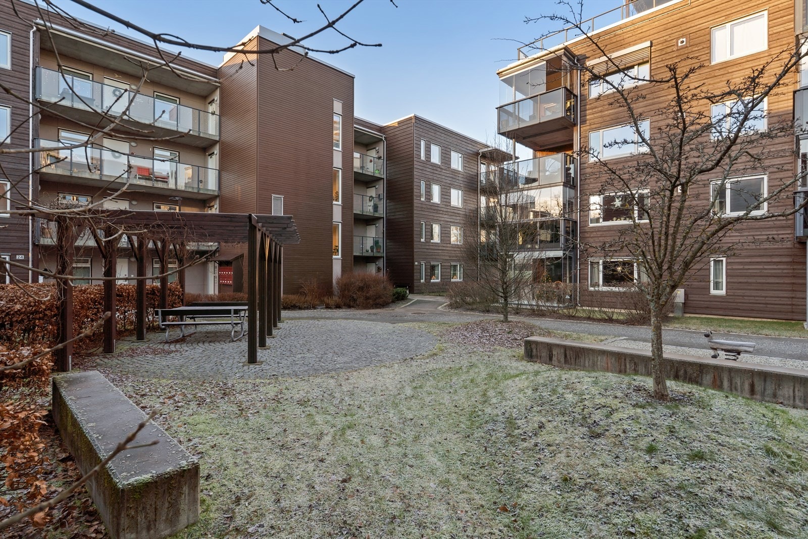 Pent opparbedet fellesareal med asfalterte internveier, gressplener, sittegrupper og pen beplantning Galleribilde