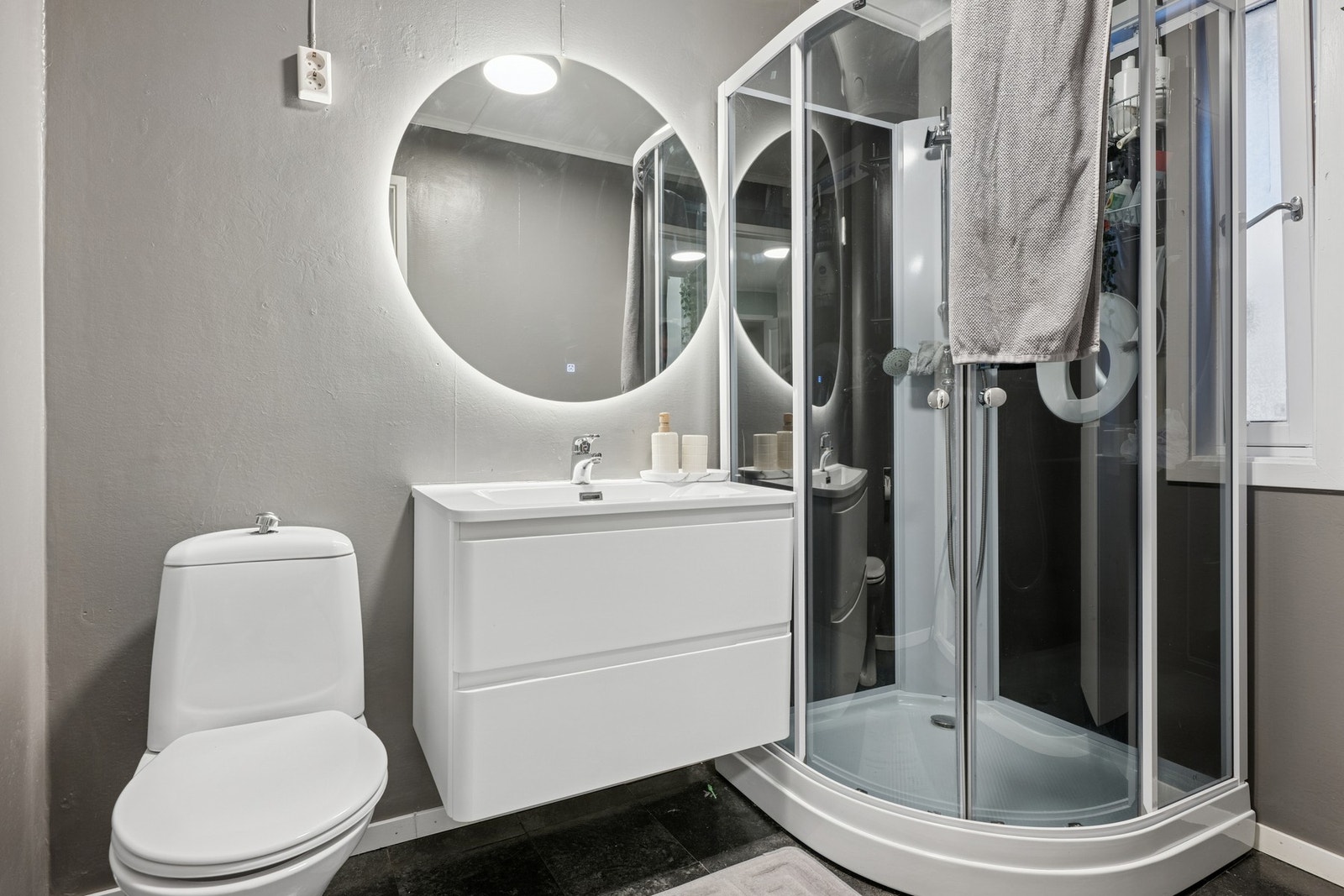 Bad med servantinnredning, toalett og dusjkabinett. Gulvet har vinylbelegg. Galleribilde