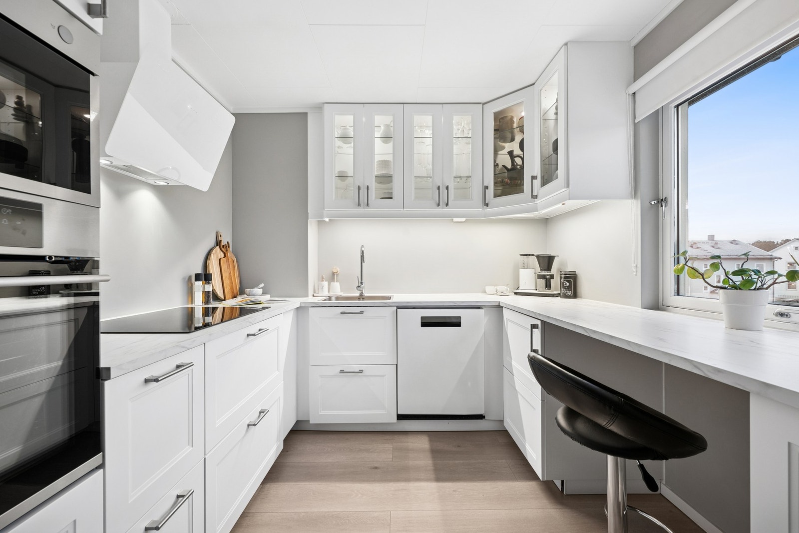 Moderne kjøkken fra 2022 med hvit innredning, laminatbenkeplate og kjøkkenventilator med avtrekk. Galleribilde