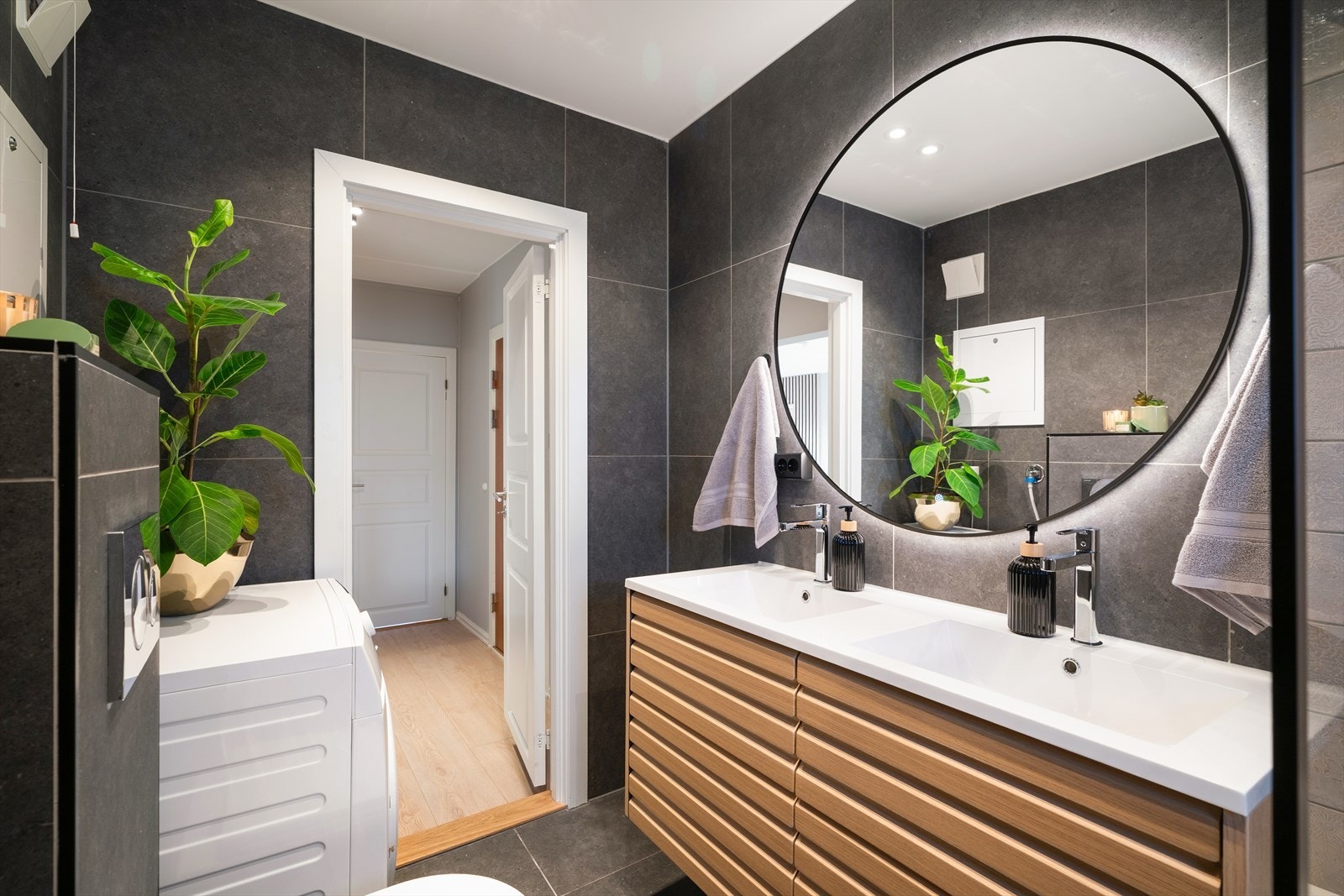 Speil over servant med innebygget lys. Rommet har innebygd badekar med regnfallsdusj, samt opplegg for vaskemaskin. Galleribilde