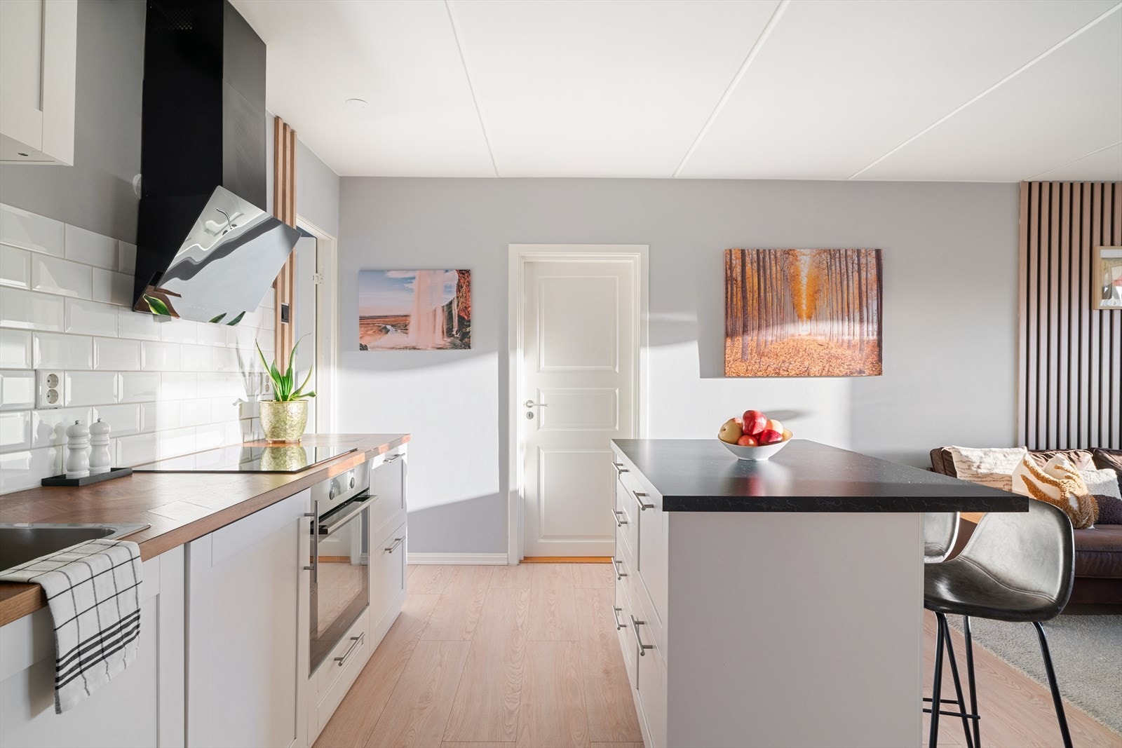 Pent kjøkken med slette fronter og fliser over benk. Galleribilde