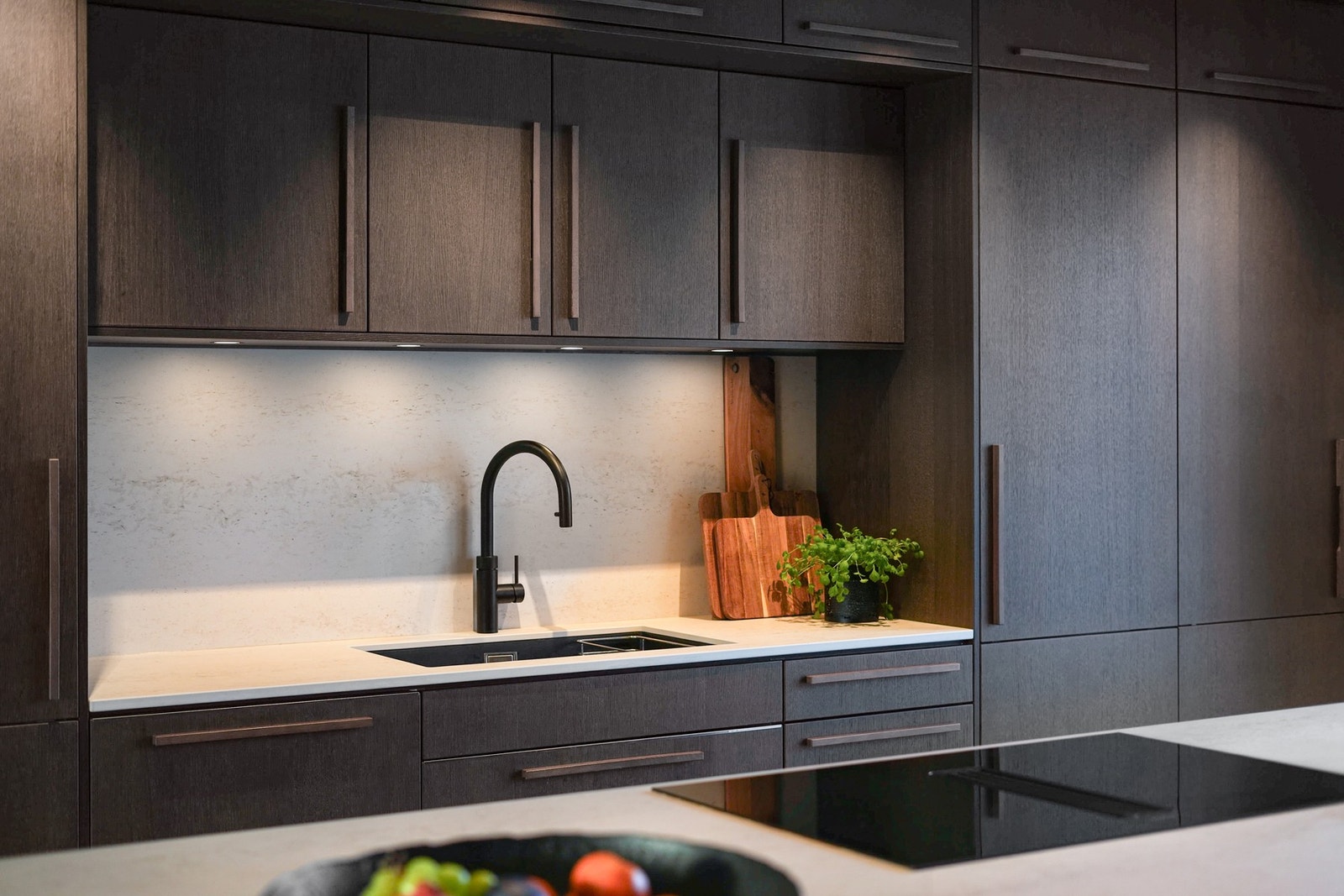 Skapene er takhøye, og benkeplaten av Decton stein fortsetter opp på veggen for et helhetlig uttrykk. Galleribilde