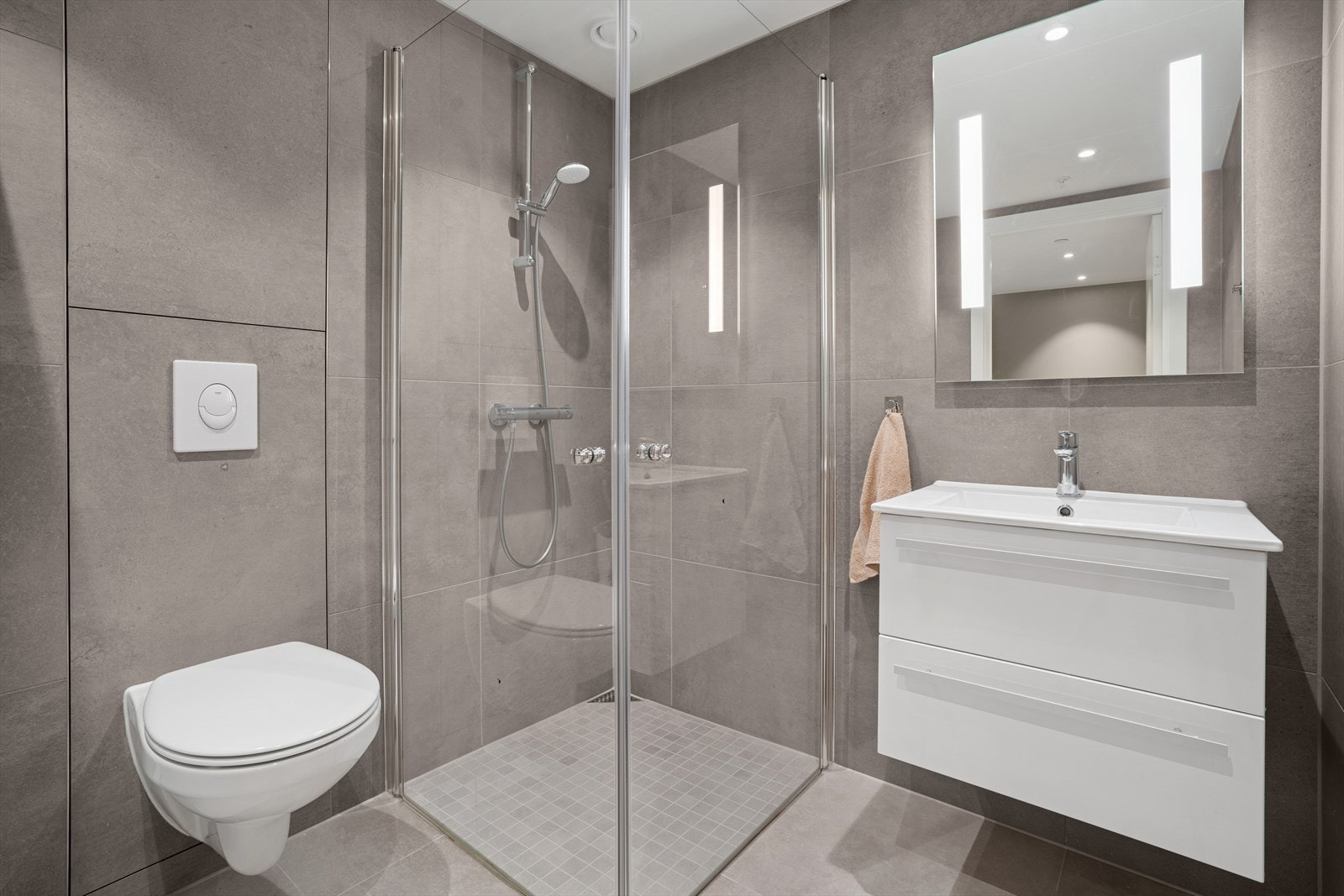 Badet holder en moderne og stilren standard med store grå fliser på både gulv og vegger Galleribilde