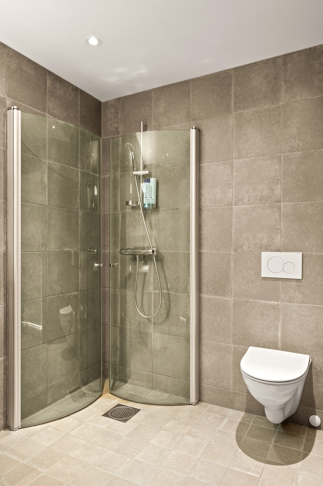 Her er det veggmontert toalett og et dusjhjørne med innfellbare glassdører. Galleribilde