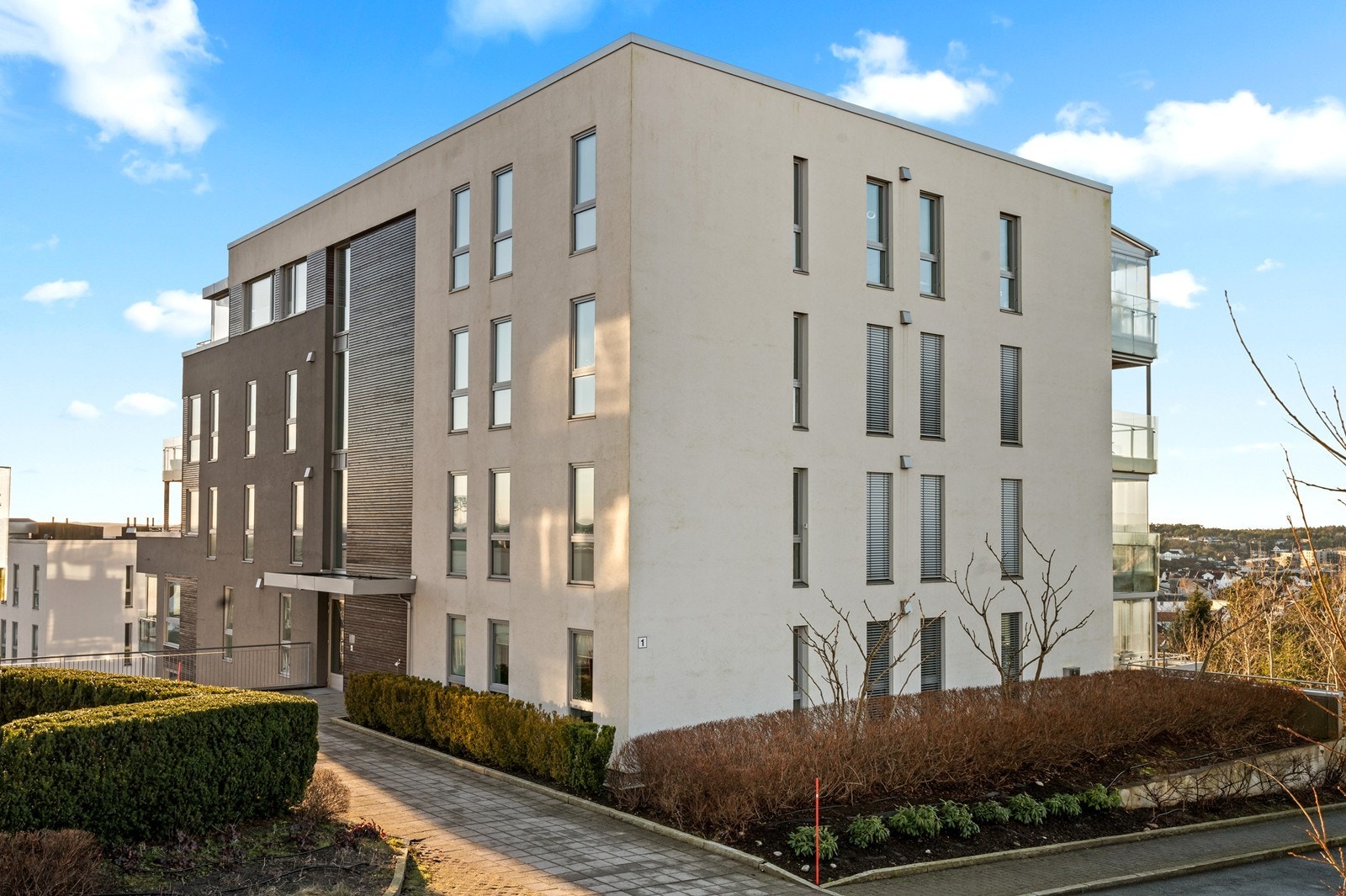 Fasaden har en kombinasjon av pussede flater og liggende trepanel. Galleribilde