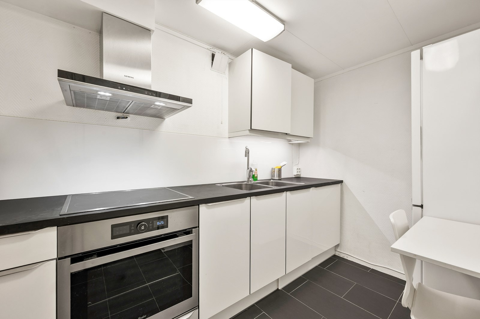 Kjøkkenet i kjeller med spiseplass har induksjonstopp, stekeovn, oppvaskmaskin og avtrekksvifte. Varmekabler i gulv. Galleribilde