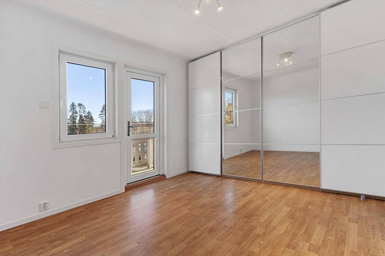 Romslig garderobeløsning med skyvedører i hvit utførelse og speilfronter Galleribilde