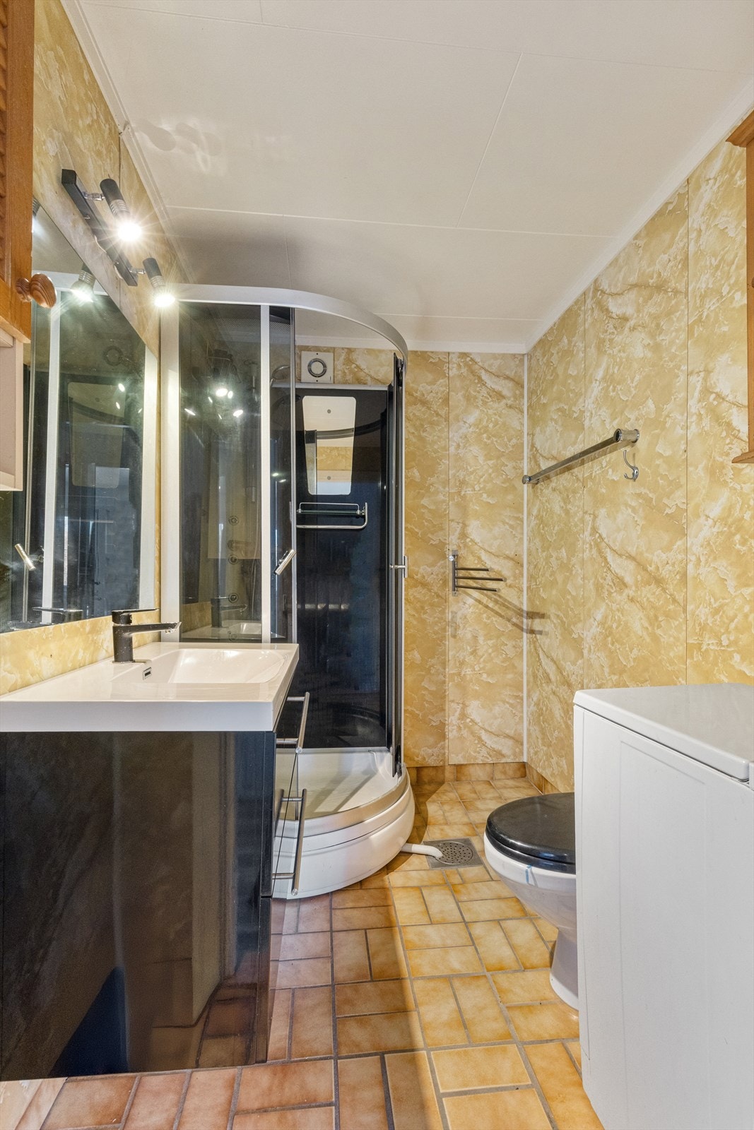 Badet har dusjkabinett, gulvstående toalett og opplegg for vaskemaskin Galleribilde