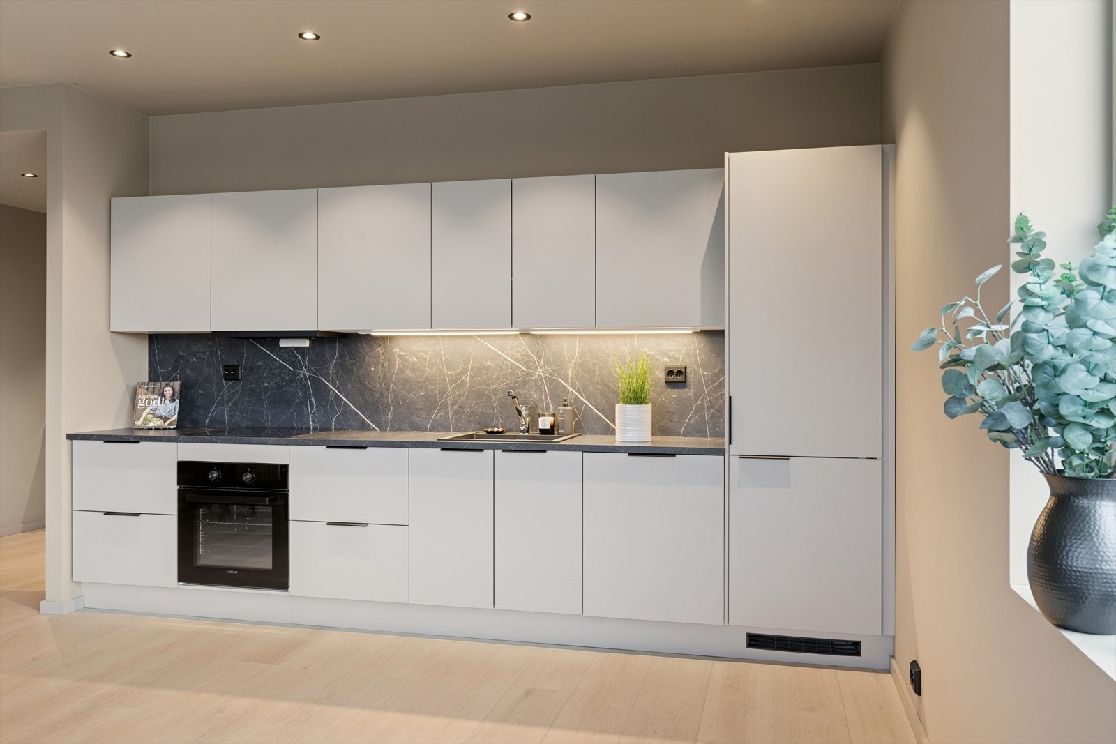 Hvitevarer er integrert og består av komfyr, platetopp, ventilator, oppvaskmaskin og kombi kjøl-/fryseskap. Galleribilde