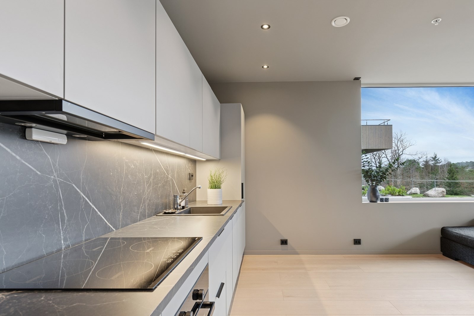 Kjøkken har innredning med hvite glatte fronter og laminat benkeplate som er trukket som backsplash for et stilrent uttrykk. Galleribilde