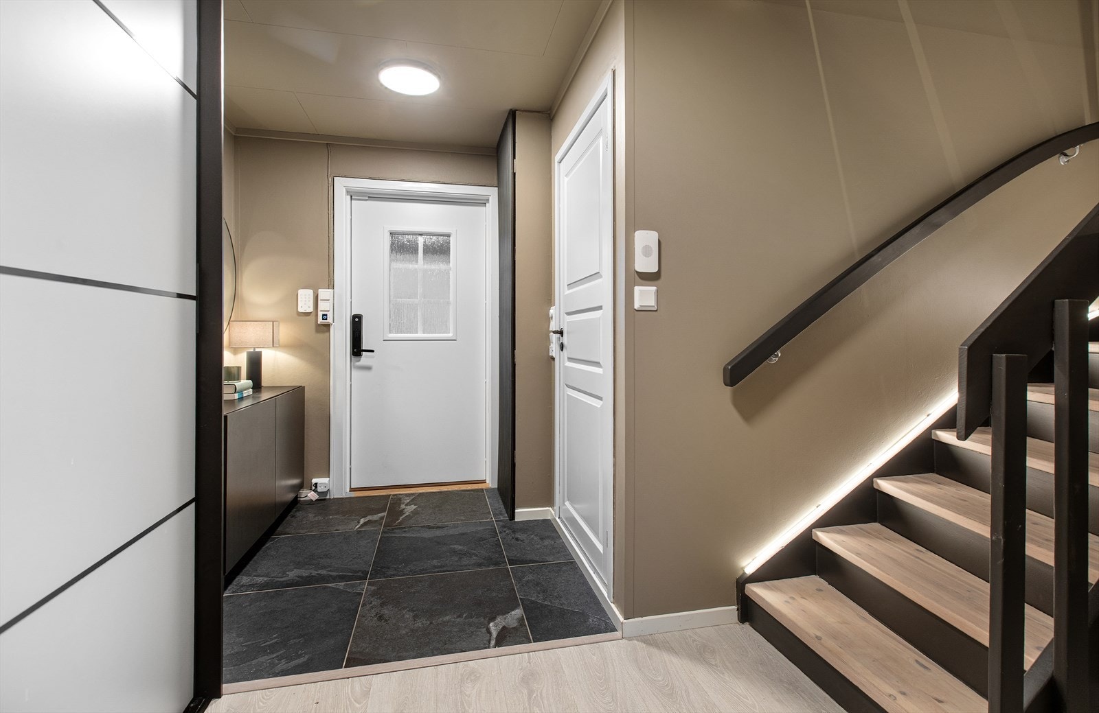 Inngangspartiet har et praktisk flislagt gulv og trapp med integrert belysning. Galleribilde
