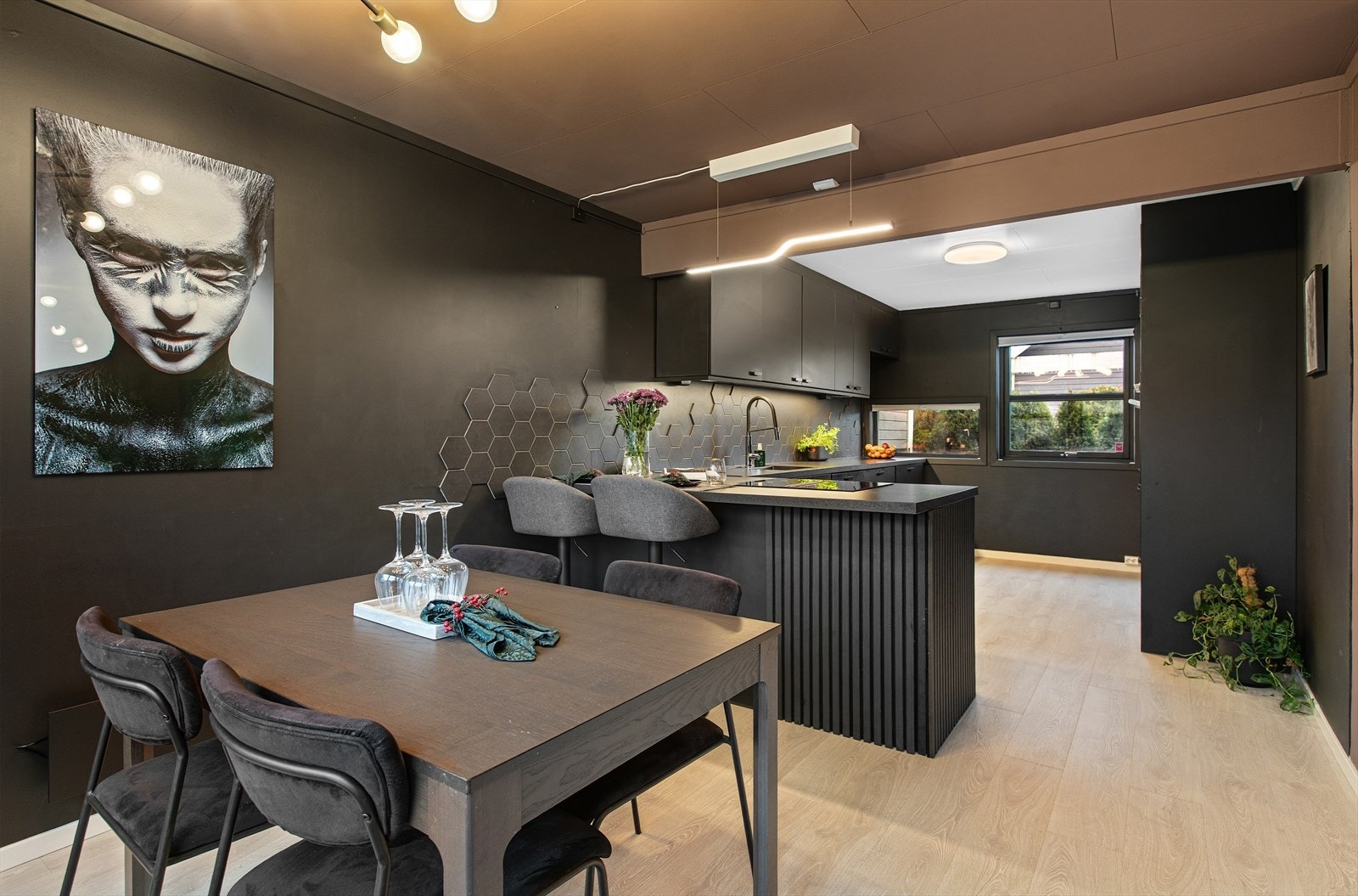 Det stilrene kjøkkenet har en gjennomgående mørk fargepalett og en sentral kjøkkenøy. Galleribilde