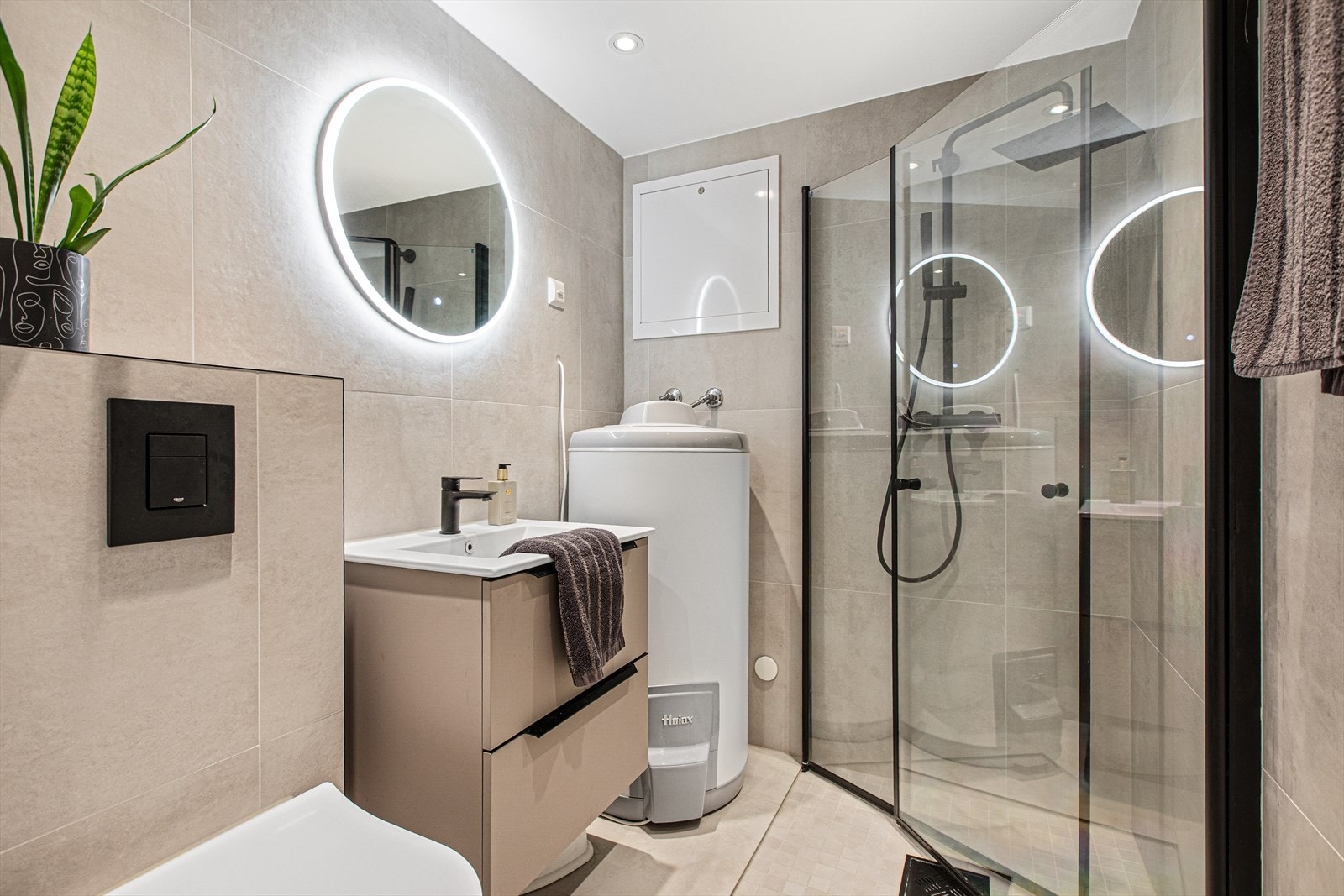 Boligen har ytterligere et bad, med lyse fliser og dusjhjørne med innfellbare dører. Galleribilde