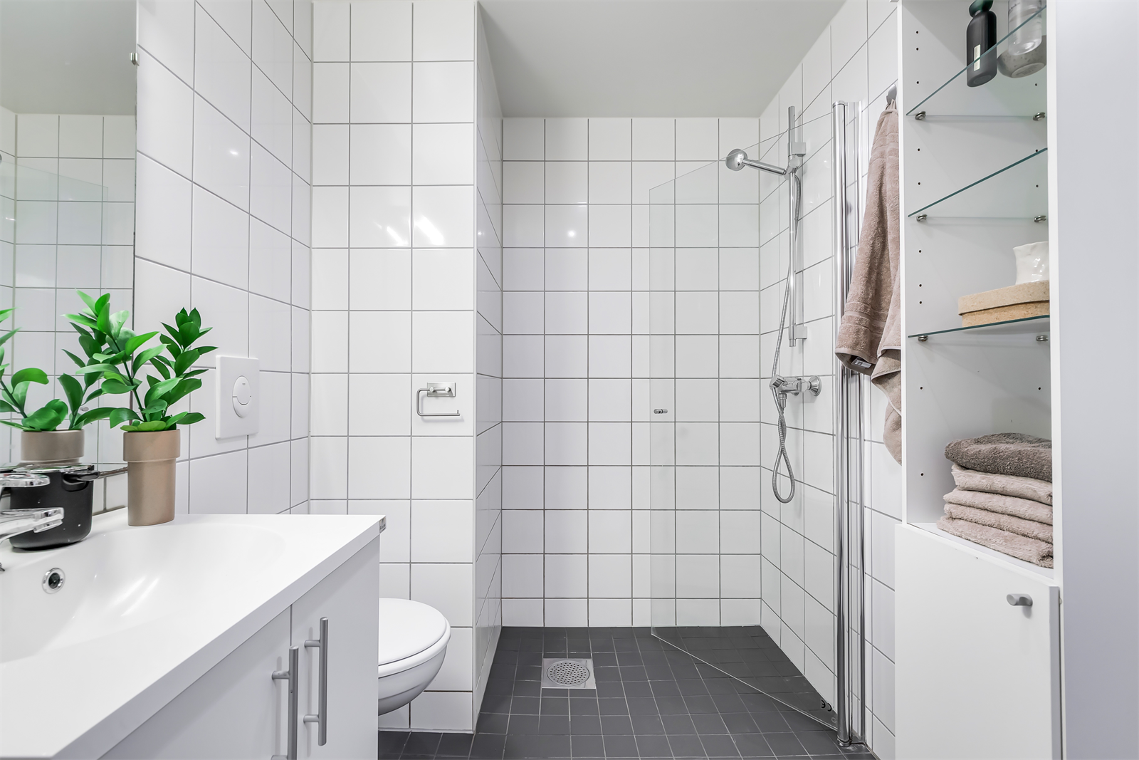 Vegghengt toalett, servant med skap for oppbevaring og romslig dusjnisje. Galleribilde