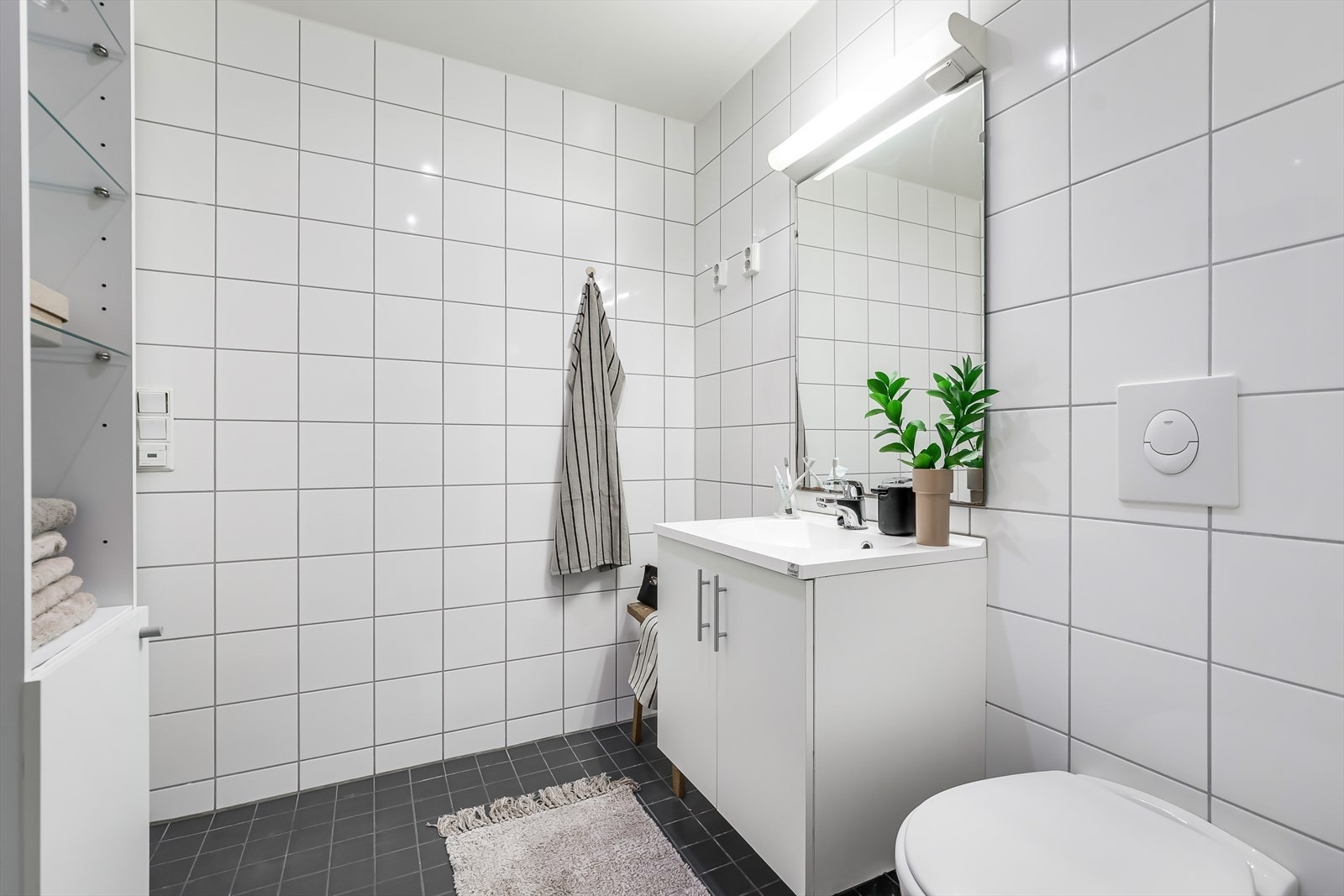 Badet er fra 2014 og har flislagte overflater, downlights i taket og behagelig gulvvarme. Det er opplegg for både vaskemaskin og tørketrommel ved servanten. Galleribilde