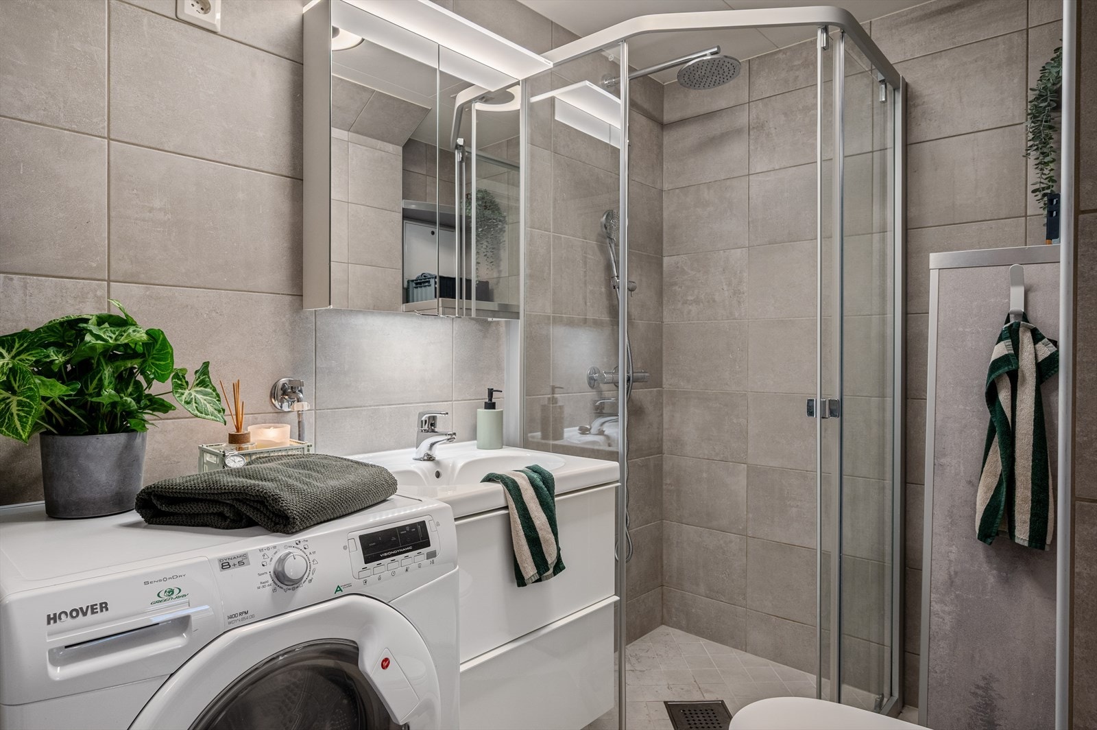 Helfliset bad innredet med baderomsmøbel med servant, speilskap med belysning, dusjhjørne og opplegg for vaskemaskin. Badet ble pusset opp i 2018 og har elektriske varmekabler i gulv. Galleribilde