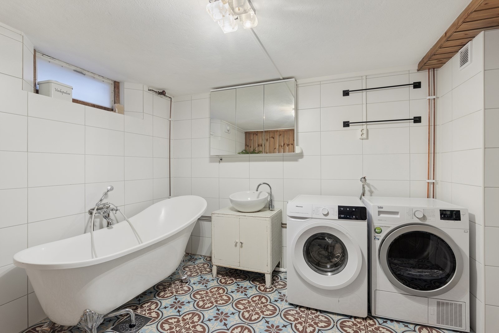 Her har man et koselig baderom med tilhørende opplegg for vaskemaskin og tørketrommel Galleribilde