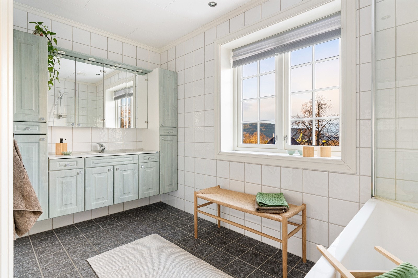 Romslig flislagt baderom på 8 kvm med toalett, dusj- og badekarløsning og servant med underbygg. Galleribilde