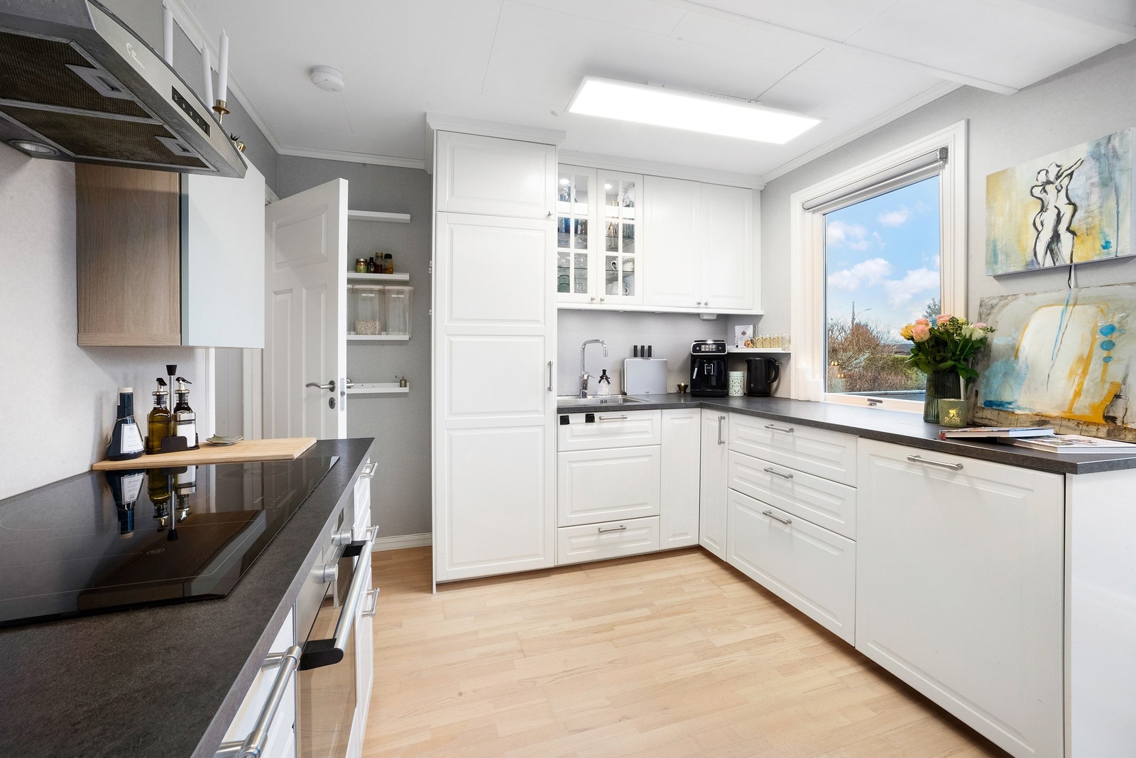 Kjøkkenet har hvite, profilerte fronter og benkeplate i laminat Galleribilde