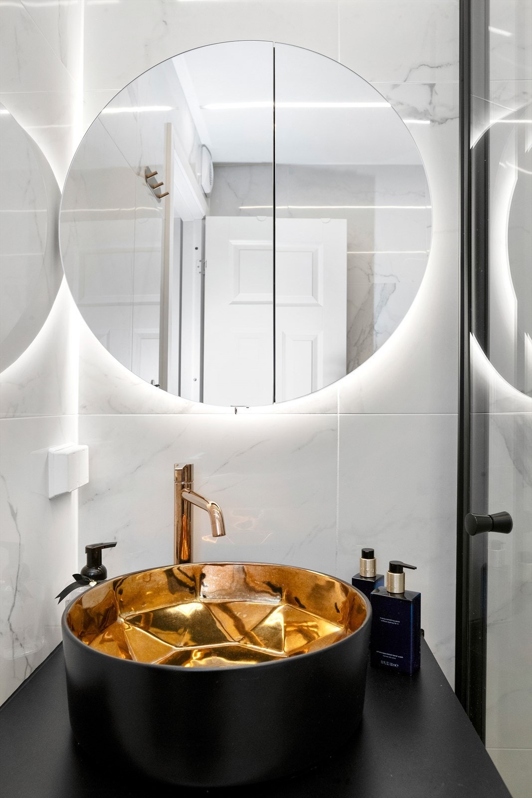 Badet har en delikat servant og lys bak speil Galleribilde