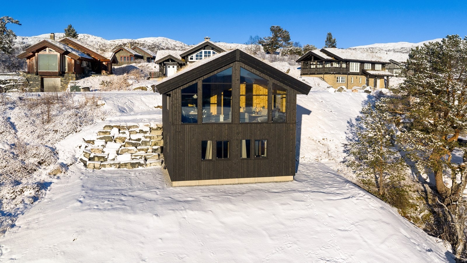 Tomten ligger i skrånende terreng og har to plan som bindes sammen av en flott forstøtningsmur i naturstein. For øvrig naturtomt. Galleribilde