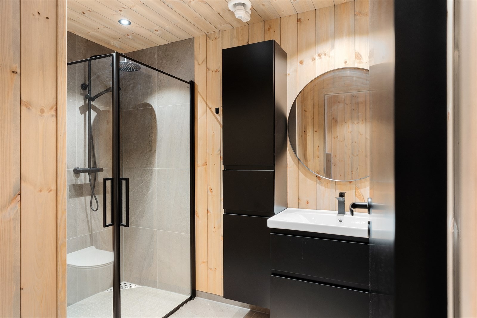 Badet i underetasjen er innredet med dusjnisje, veggmontert toalett og baderomsinnredning med heldekkende servant. Galleribilde