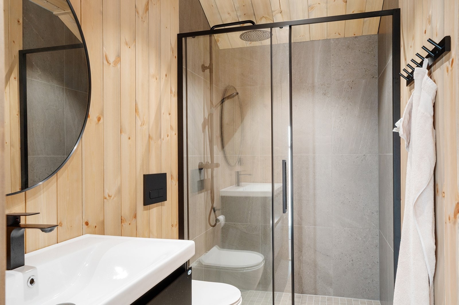 Delikat baderom i hovedetasjen, innredet med dusjnisje, veggmontert toalett og baderomsinnredning med heldekkende servant. Galleribilde