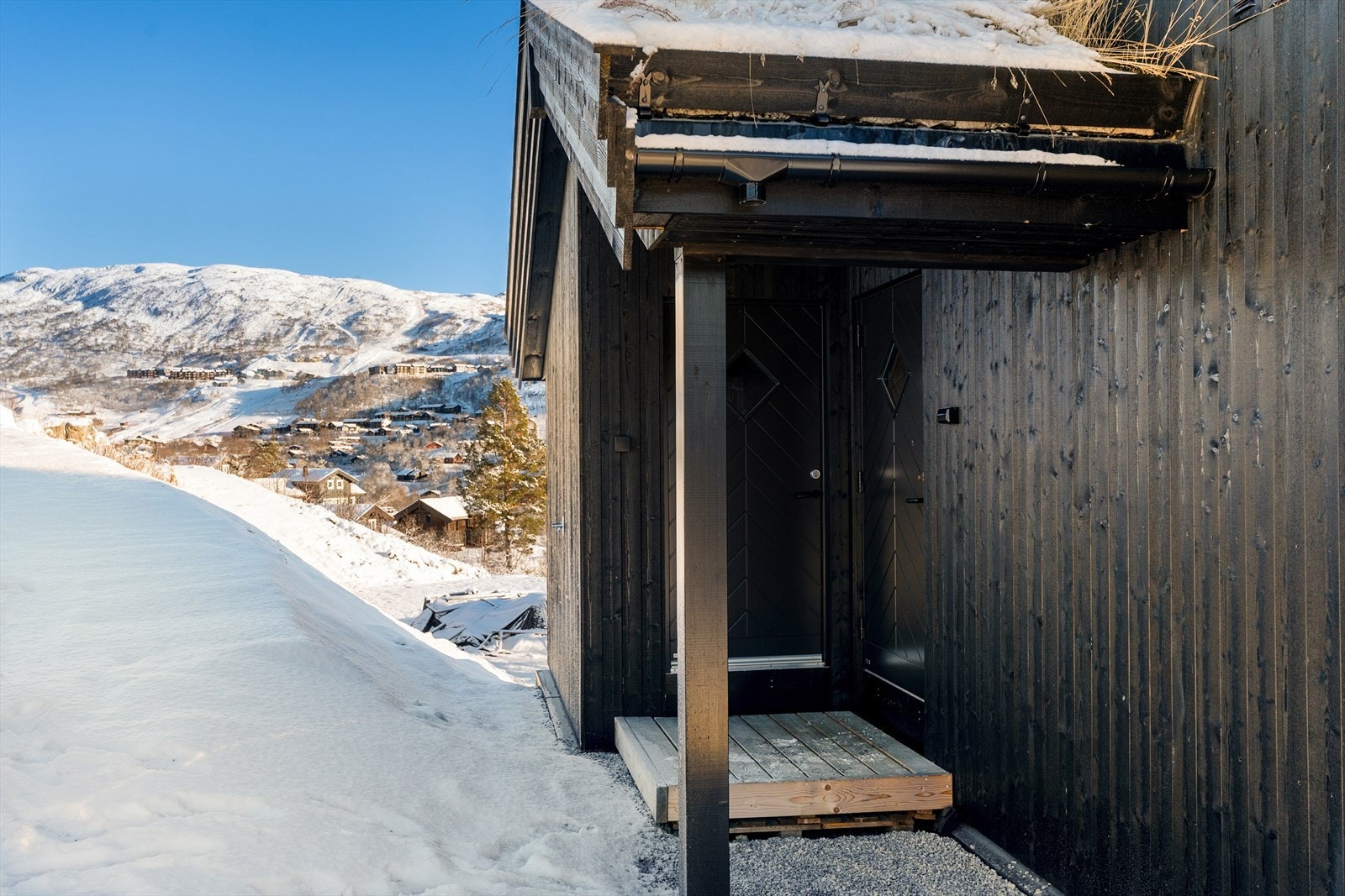 Overbygget inngangsparti med hovedinngang og bi-inngang til romslig bod. Galleribilde