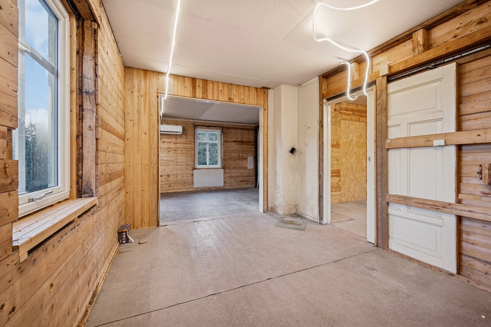 Hele 1. etg fremstår som et råbygg, med åpne rom, ubehandlede trepanelvegger og sponplater på gulv - alt klart for videre oppbygging og innredning etter eget ønske. Galleribilde