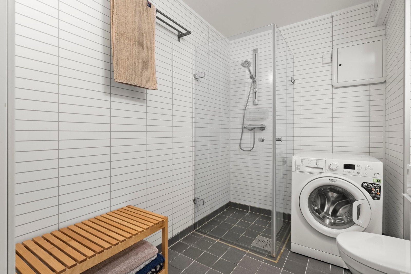 Badet er utstyrt med vegghengt toalett, dusjløsning, servant med innredning og opplegg for vaskemaskin og tørketrommel. Galleribilde