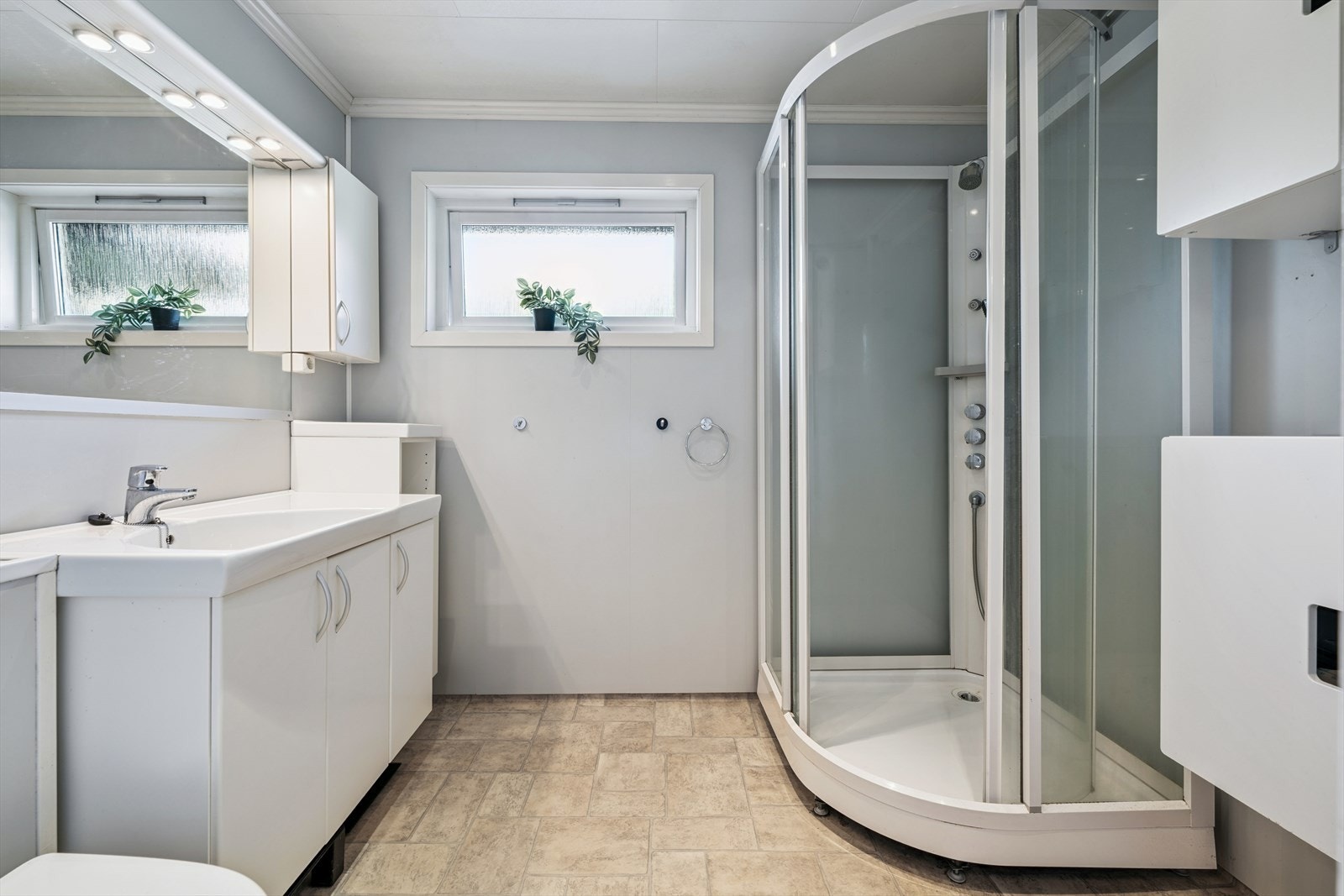 Pent bad med dusjkabinett, vegghengt wc og innredning med vask. Galleribilde