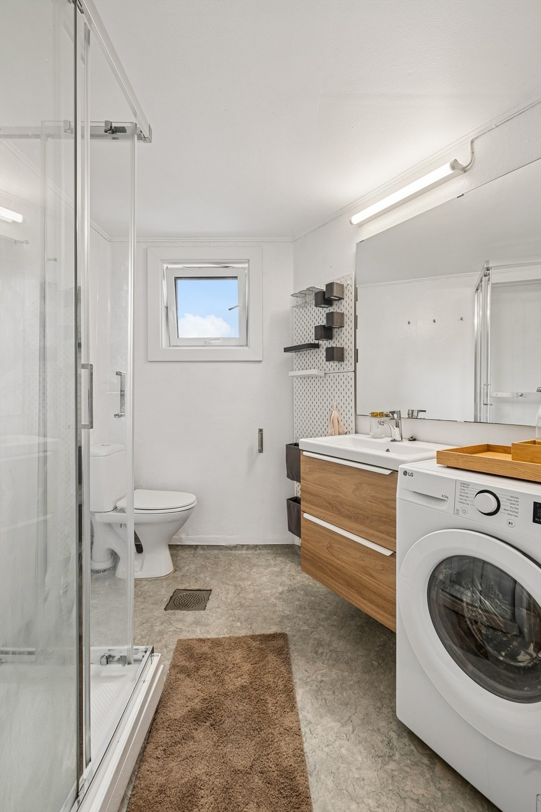 Godt utnyttet baderom med belegg på gulv, toalett, dusjkabinett, nyere servant og opplegg til vaskemaskin Galleribilde