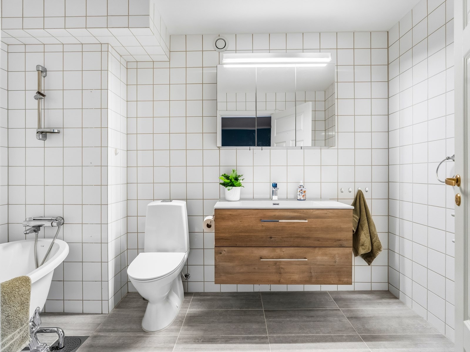 Badet har dusj i badekar, gulvstående klosett og servant. Galleribilde