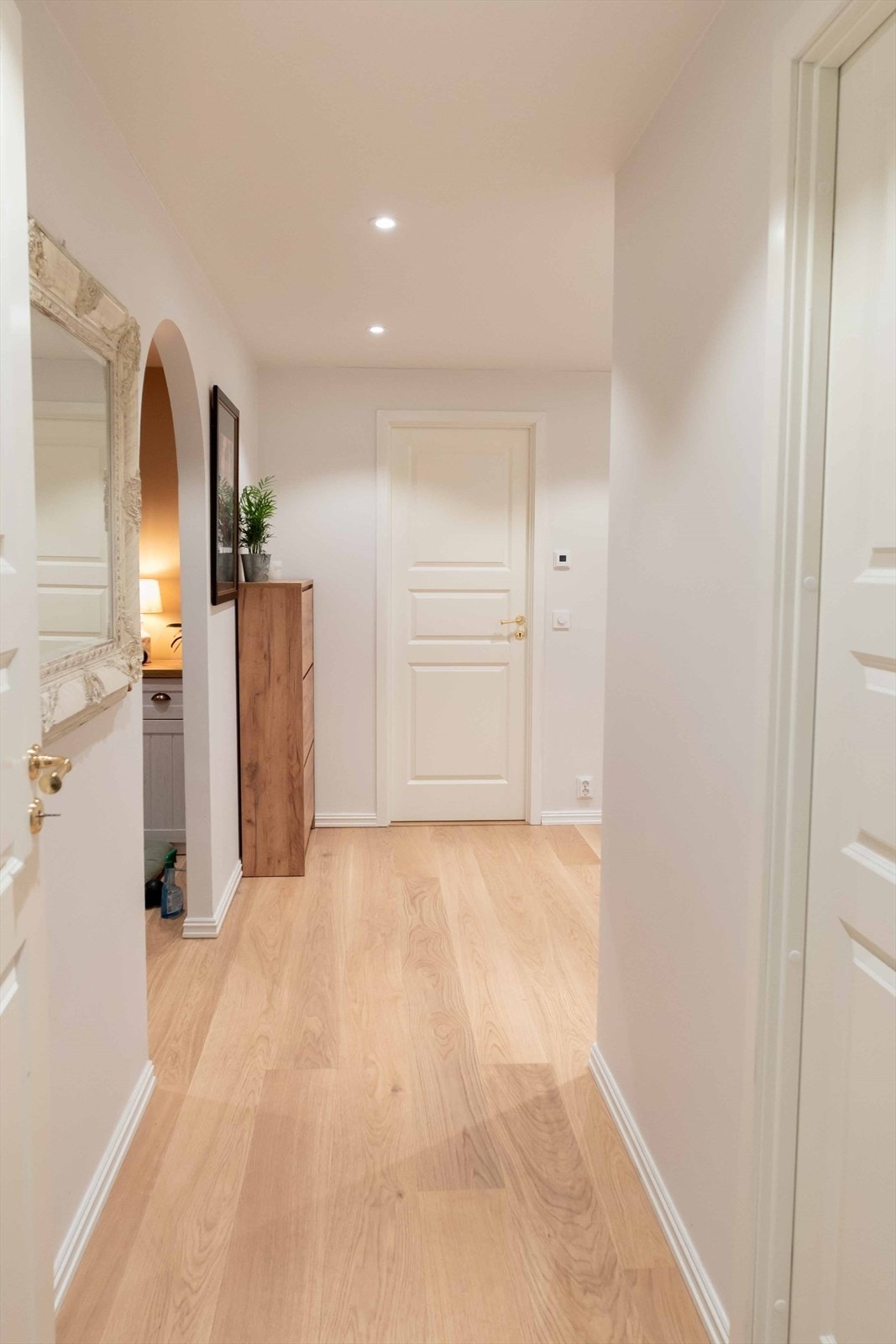 Velkommen inn! Lys gang med stilrene overflater og praktisk oppbevaringsplass. En funksjonell gjennomgangssone mellom rommene. Galleribilde