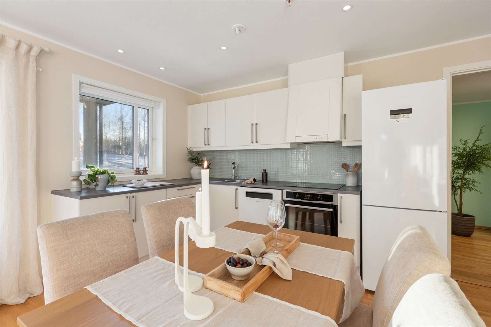 Kjøkkenet har en pen og tidløs innredning fra byggeåret, med hvite, glatte fronter og mørk laminert benkeplate med planlimt kum i kompositt. Galleribilde