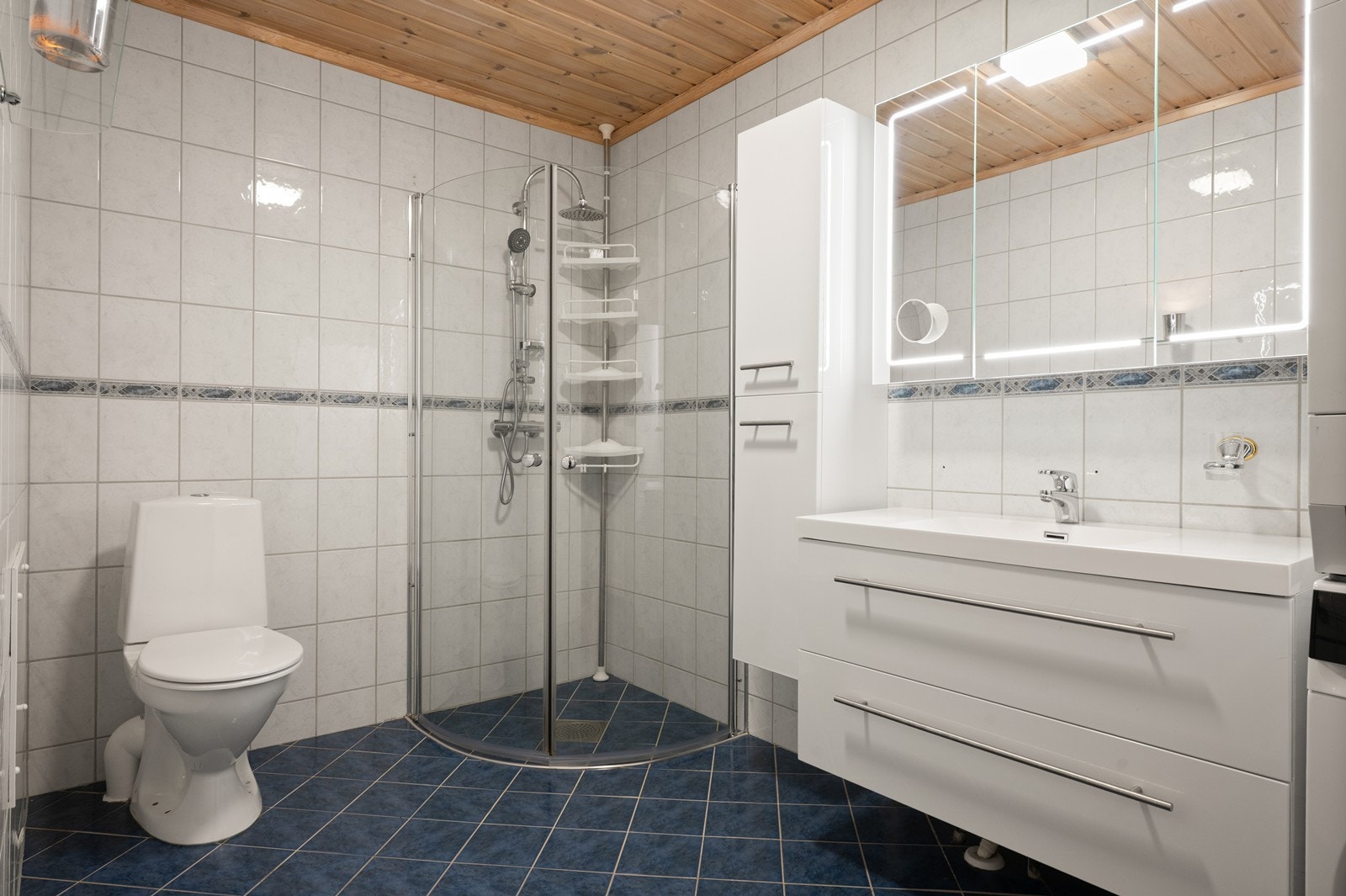 Badet i første etasje er helfliset, og har en standard i fra byggeåret 2002. Det er varmekabel i gulvet og rommet er innredet med dusjhjørne og servantinnredning. Servantinnredningen er av nyere dato. Galleribilde