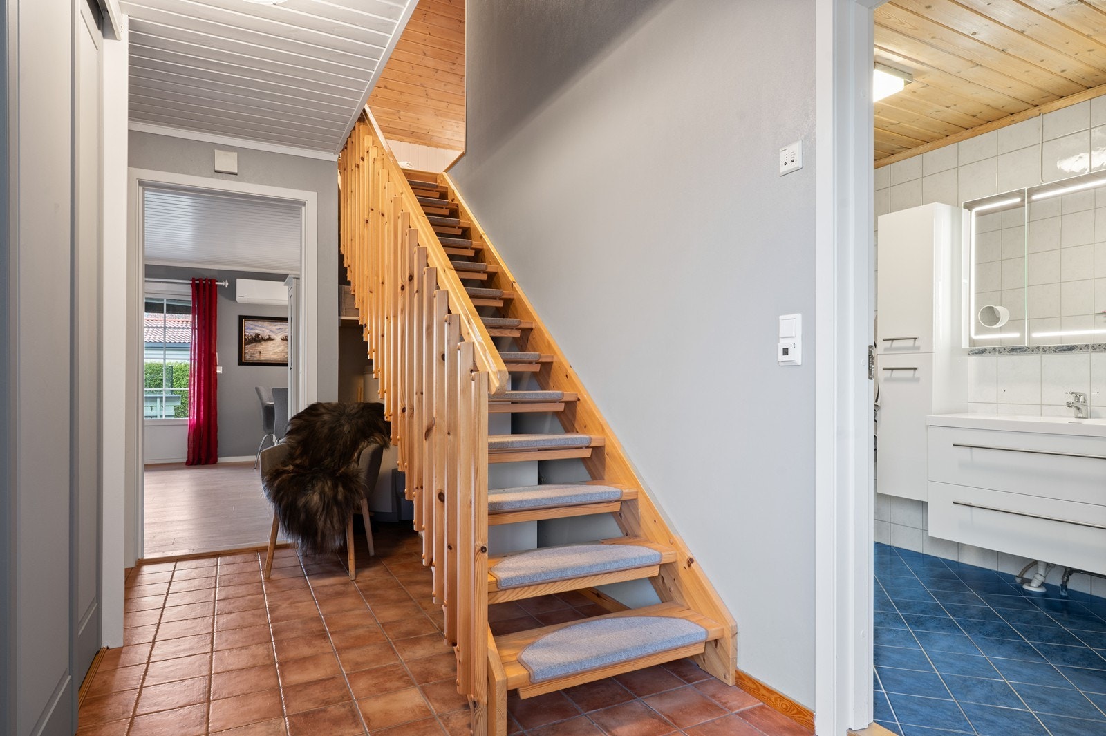 Inngangspartiet har flislagt gulv og trapp som leder opp til andre etasje. Dessuten er det en integrert skyvedørsgarderobe i gangen, for effektiv oppbevaring av klær og sko. Galleribilde