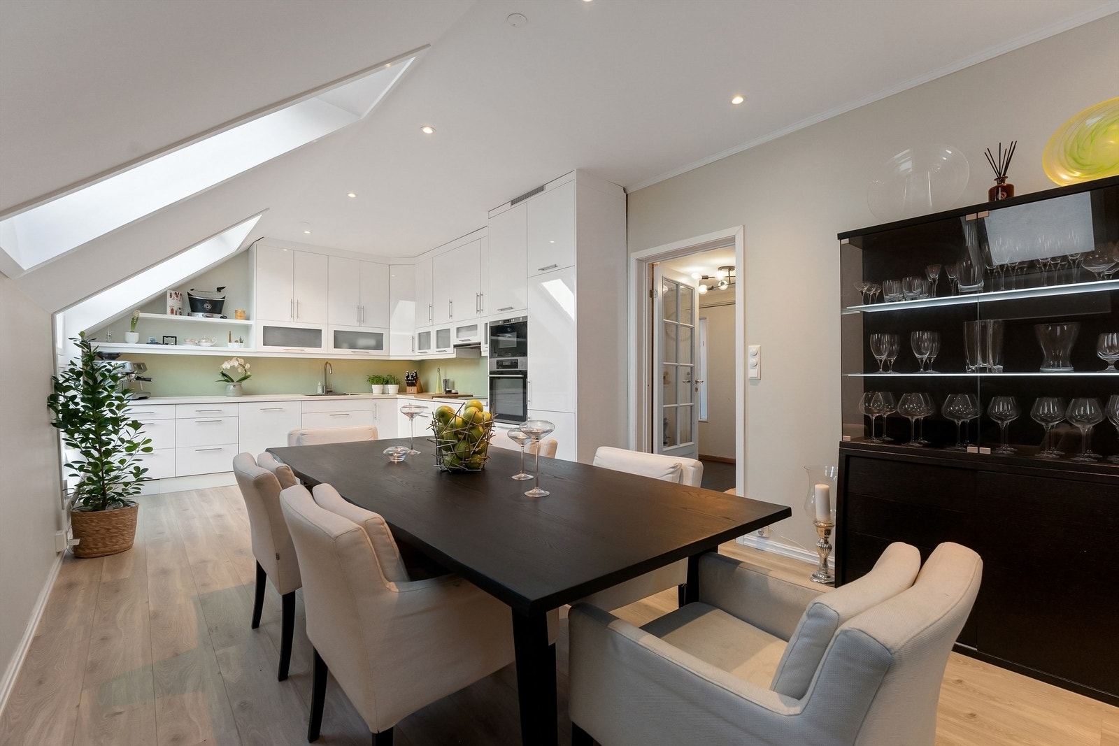 Hyggelig kjøkken med glatte fronter på skap og skuffer, benkeplater av tre med nedsenket oppvaskkum og glassplater mellom benkeplate og overskap Galleribilde