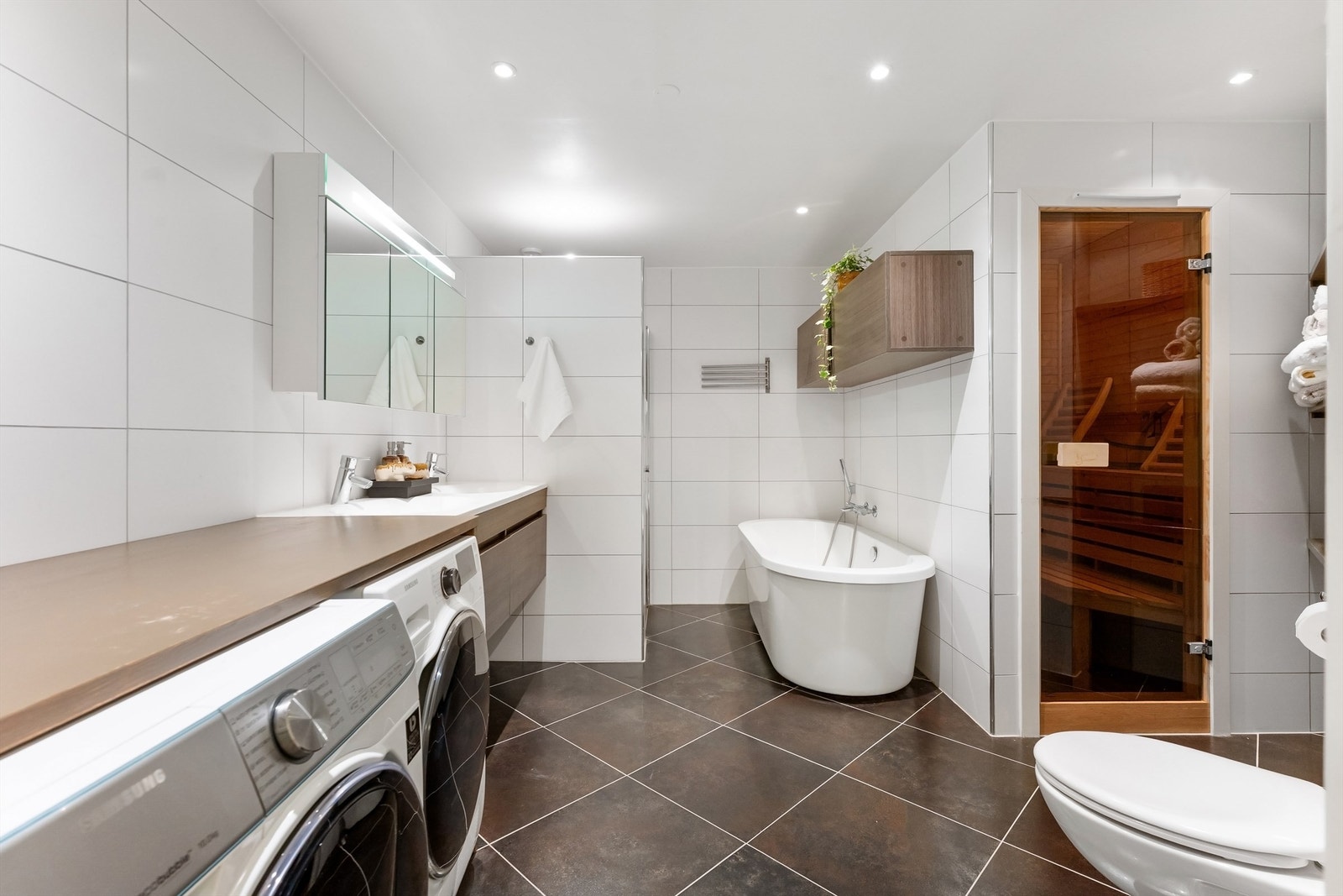 Pent baderom fra 2013 med fliser på gulv med gulvvarme, fliser på vegger og malt himling med downlights Galleribilde