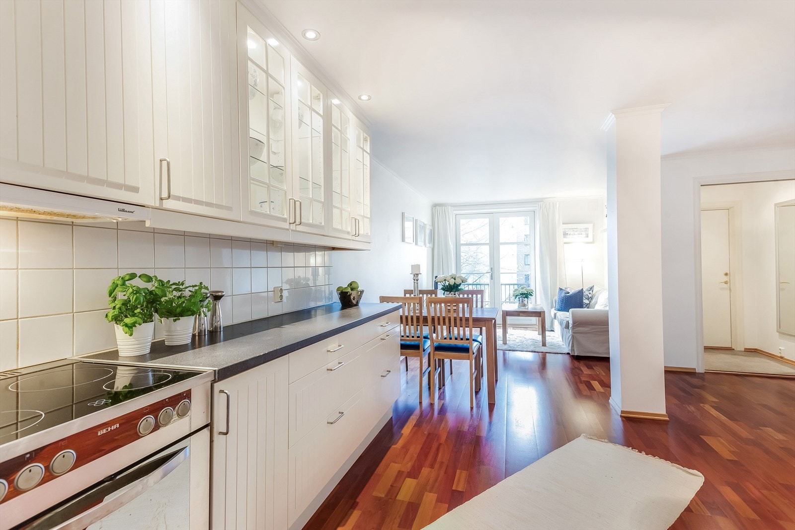 Delikat kjøkkeninnredning med hvite profilerte fronter og benkeplate av laminat. God belysning med downlights i tak. Galleribilde