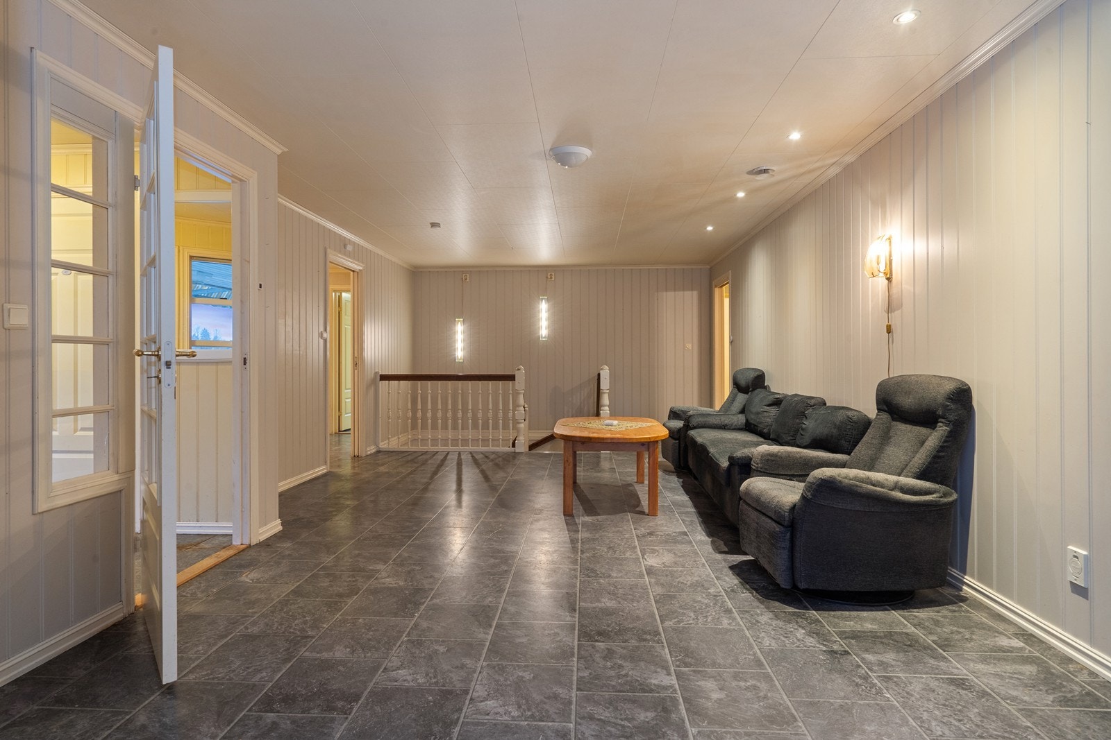 En romslig TV-stue i 1.etasje med trapp ned til underetasjen. Galleribilde