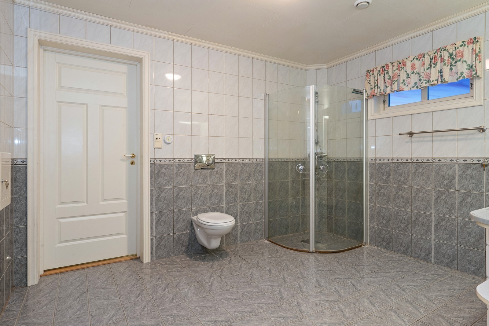 Flislagt bad i 1. etasje med dusjhjørnevegghengt toalett, skap og servantinnredning. Galleribilde