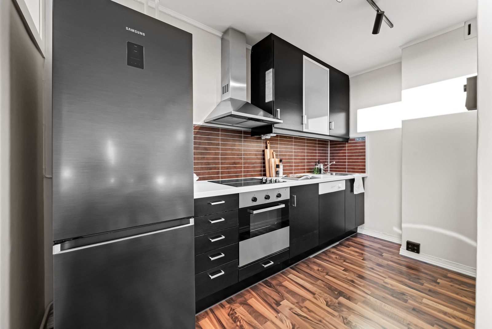 Kjøkken med benke og overskap med slette fronter og dempefunksjoner. Avsatt plass for frittstående kjøle-/fryseskap. Galleribilde