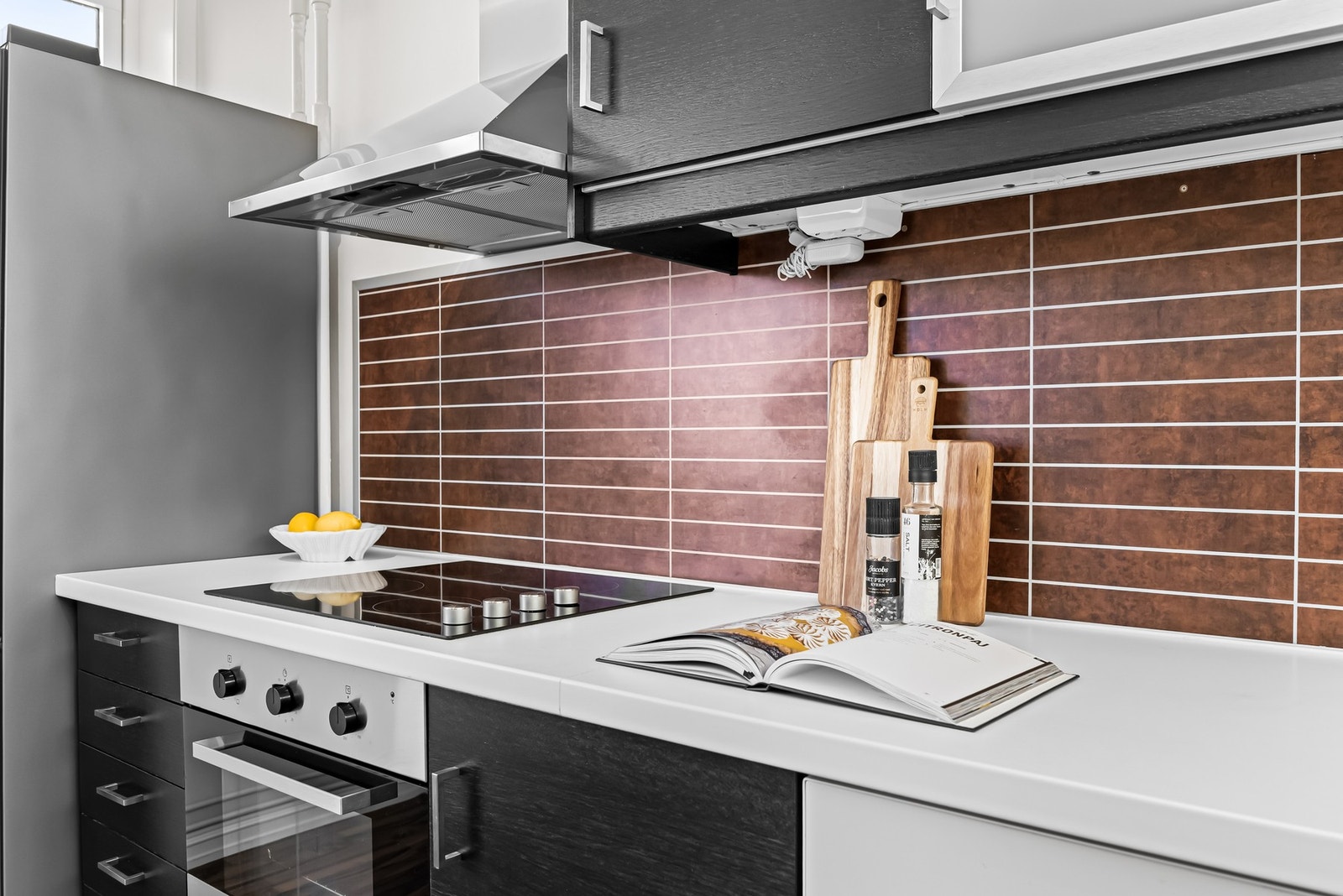 De øvrige hvitevarene er integrerte og består av koketopp, stekeovn og oppvaskmaskin. Over kokesonen er det avtrekksvifte i stålhette med kullfilter. Galleribilde