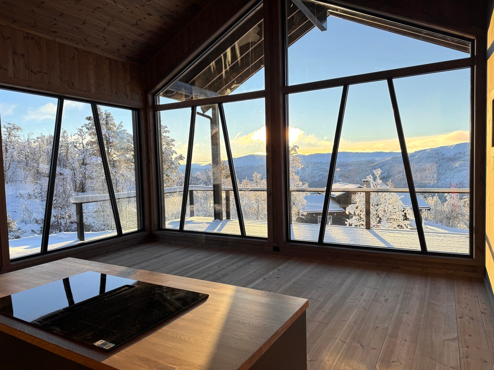 Den åpne stuen byr på utsikt mot snødekte fjell og vinterlandskap Galleribilde